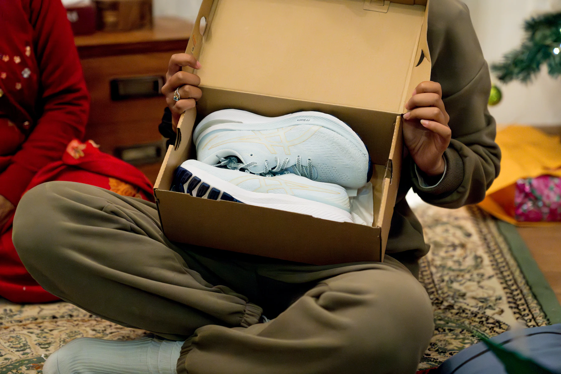 A man sitting on the floor holding a box with a baby in it