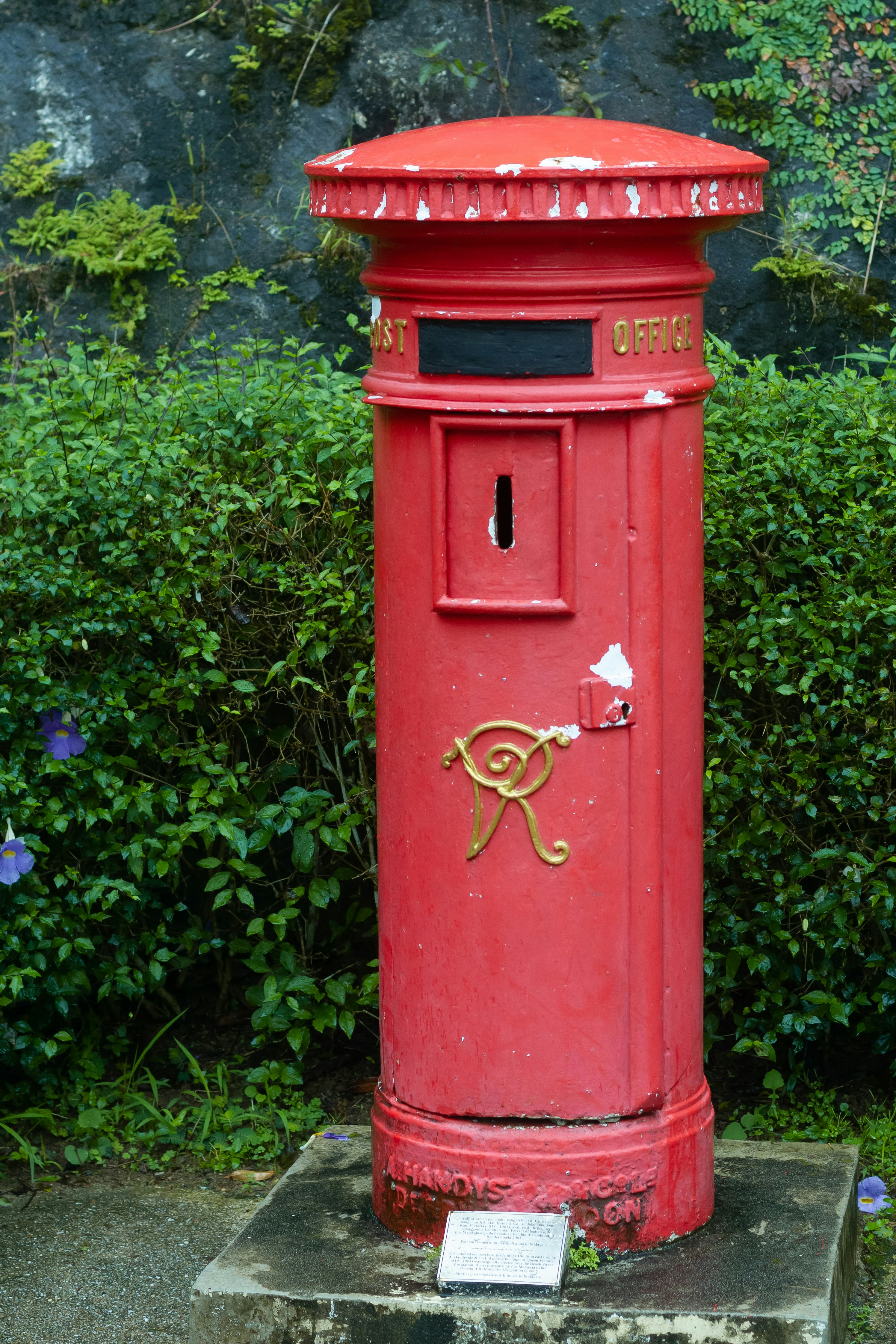 A red mailbox sitting on top of a cement slab