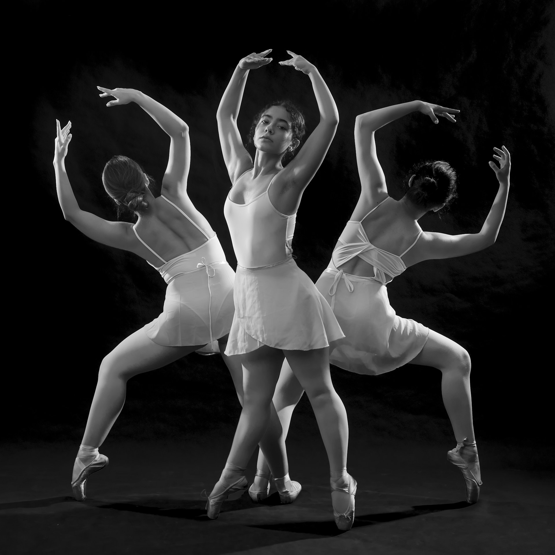 Three ballerinas are posing for a black and white photo