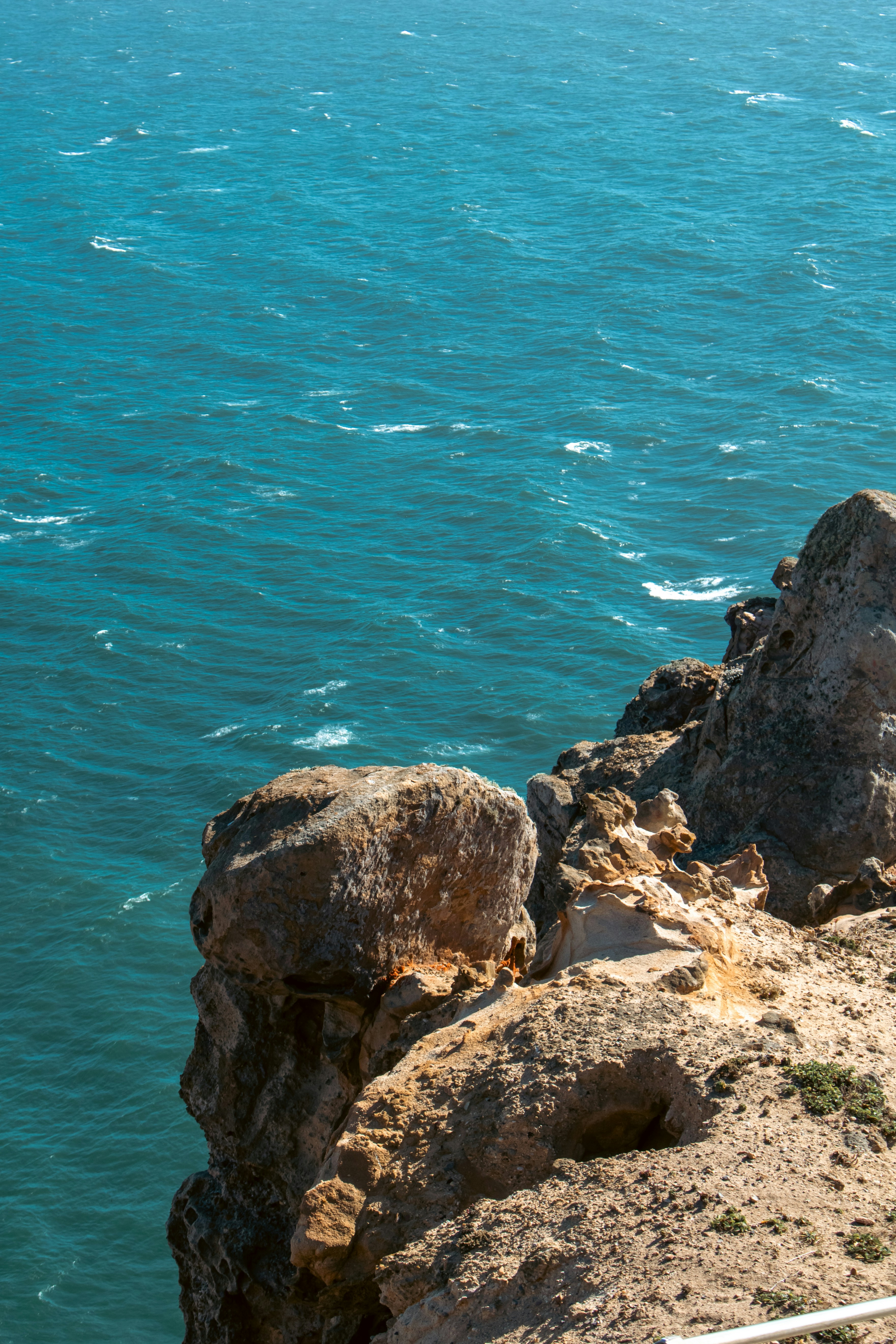A man sitting on a cliff overlooking the ocean