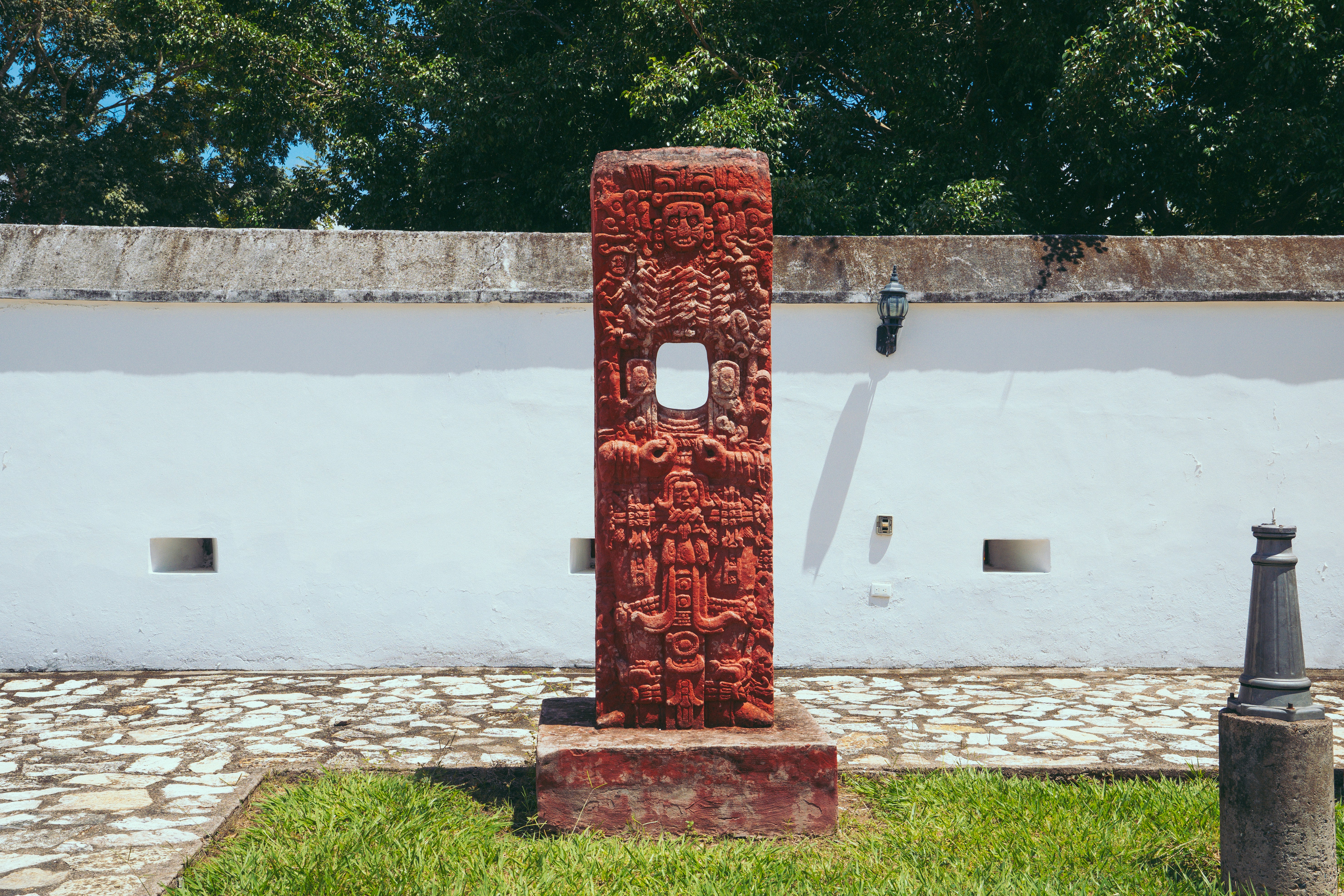 A tall red sculpture sitting in the middle of a park