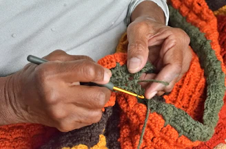 A person is crocheting a blanket with a crochet hook