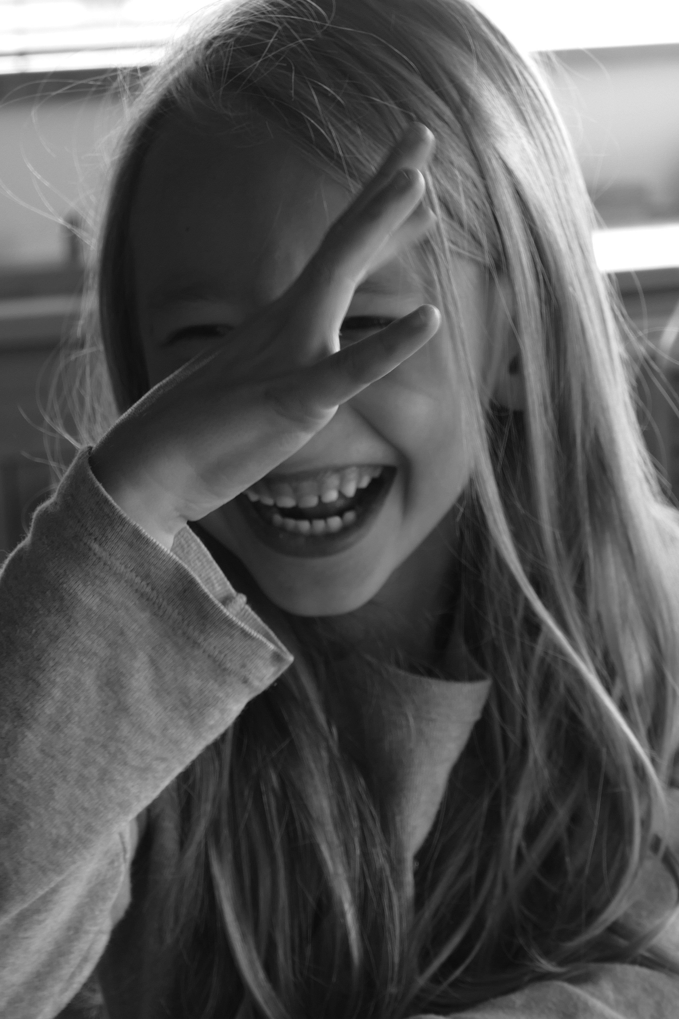 A young girl smiling and covering her eyes
