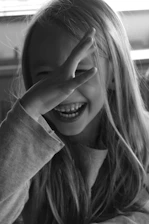 A young girl smiling and covering her eyes