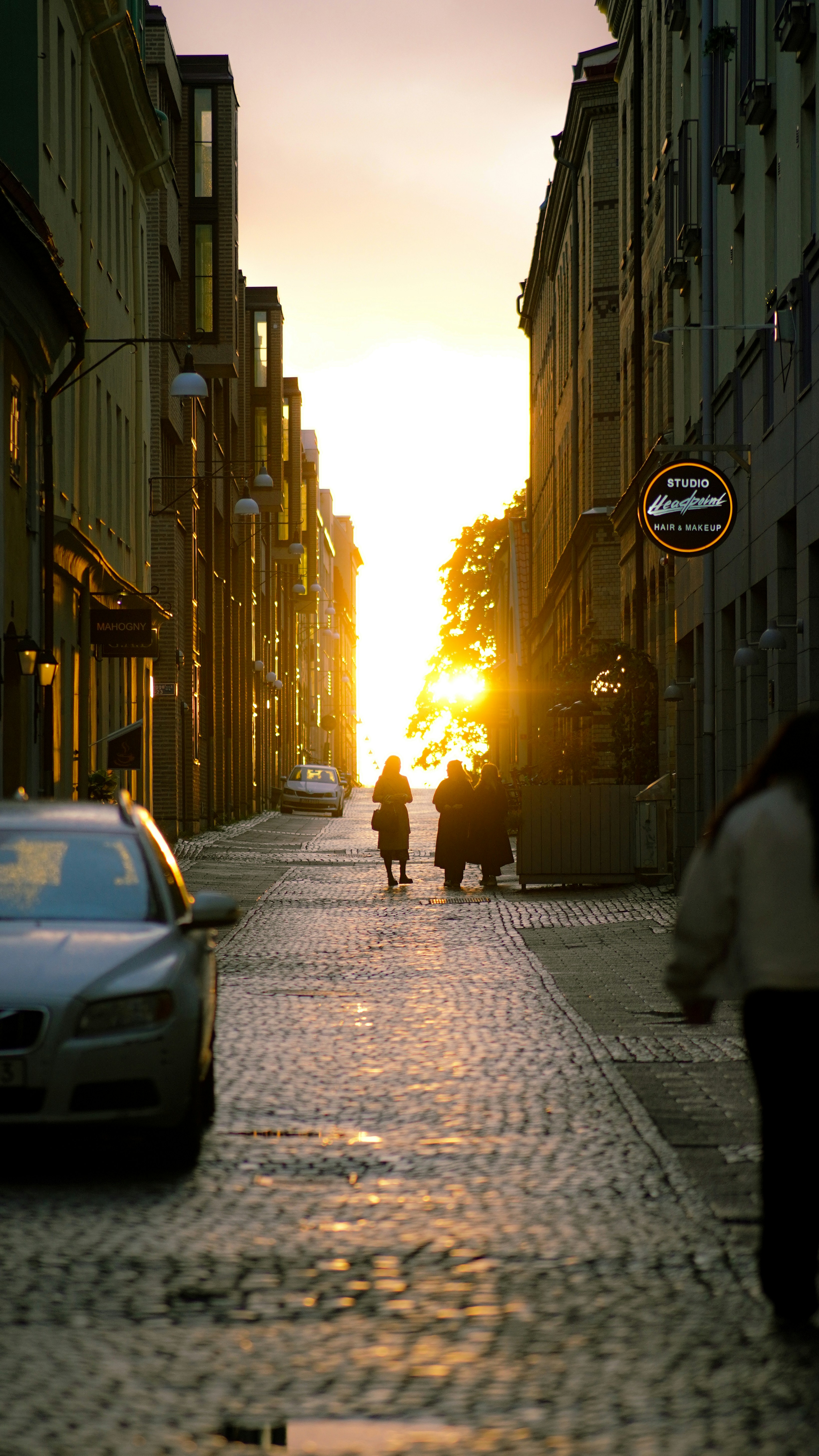 A couple of people walking down a street next to tall buildings