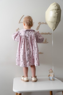 A little girl standing on a stool with a balloon