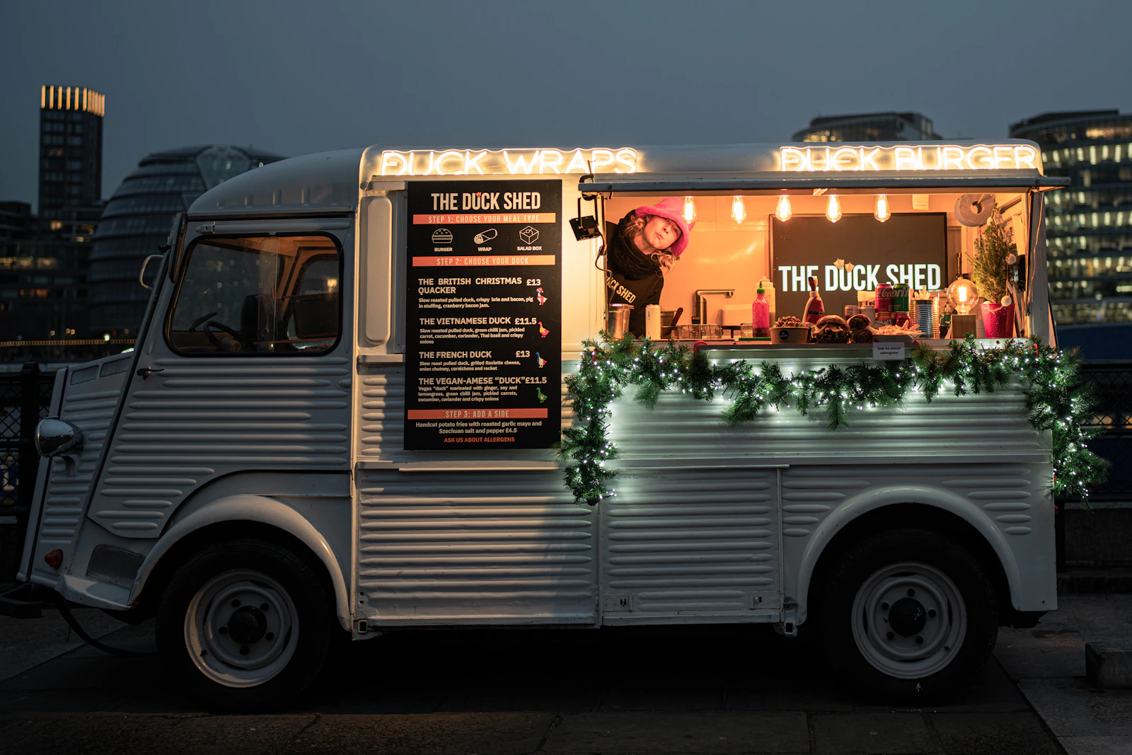 A food truck parked in front of a city skyline at golden hour