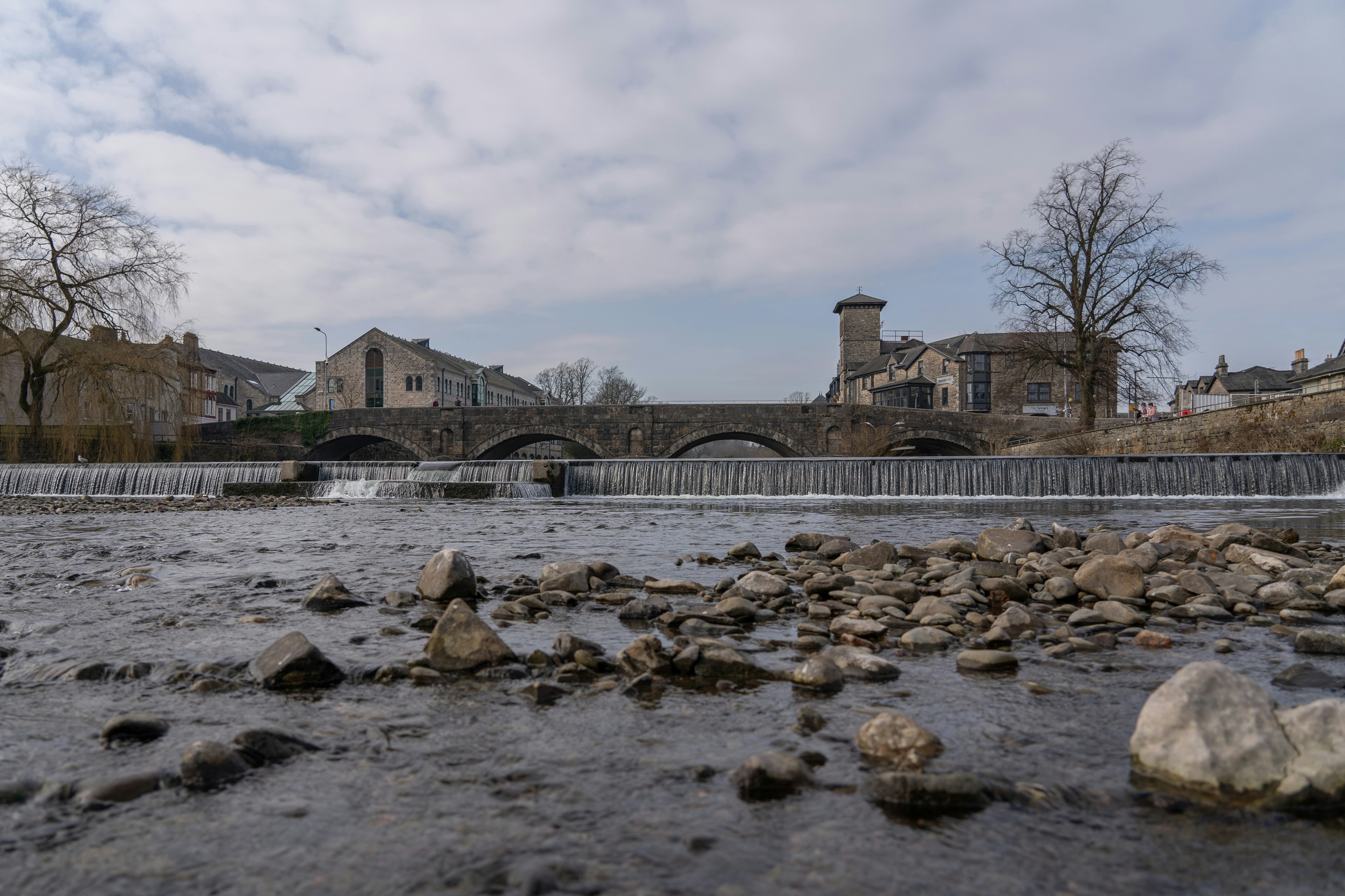 A river with rocks and a bridge in the background
