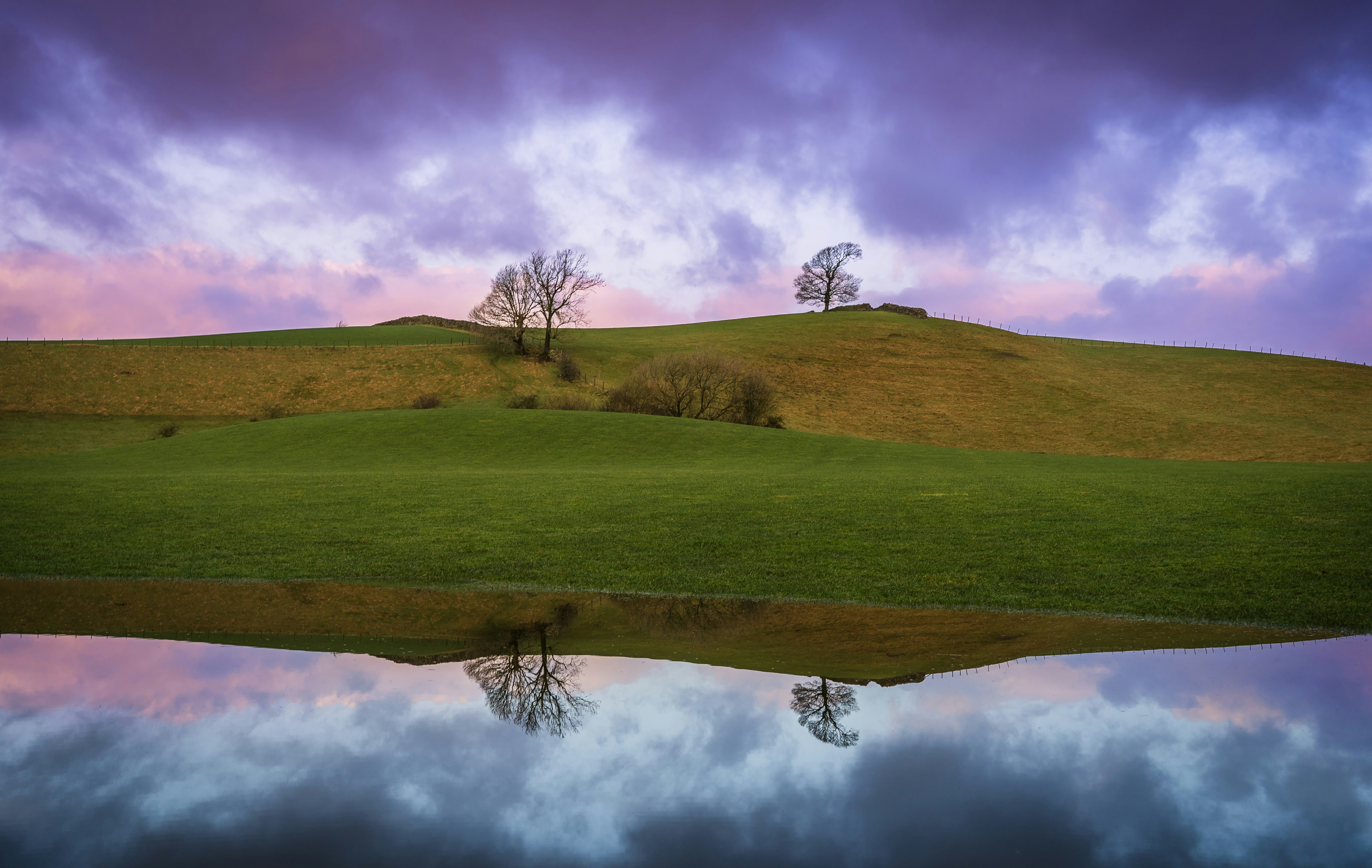A grassy hill with a lake in the foreground