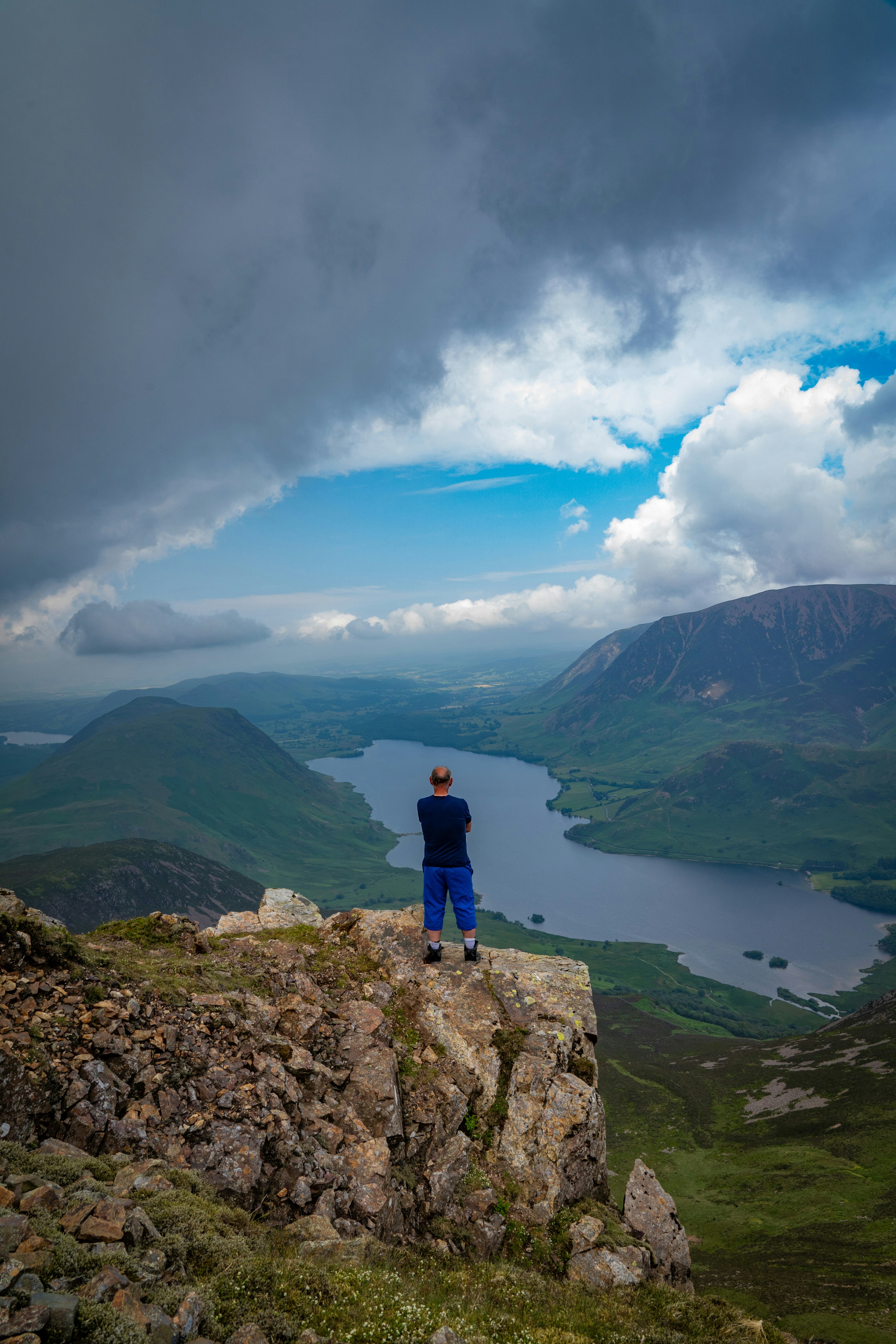 A man standing on top of a mountain overlooking a lake
