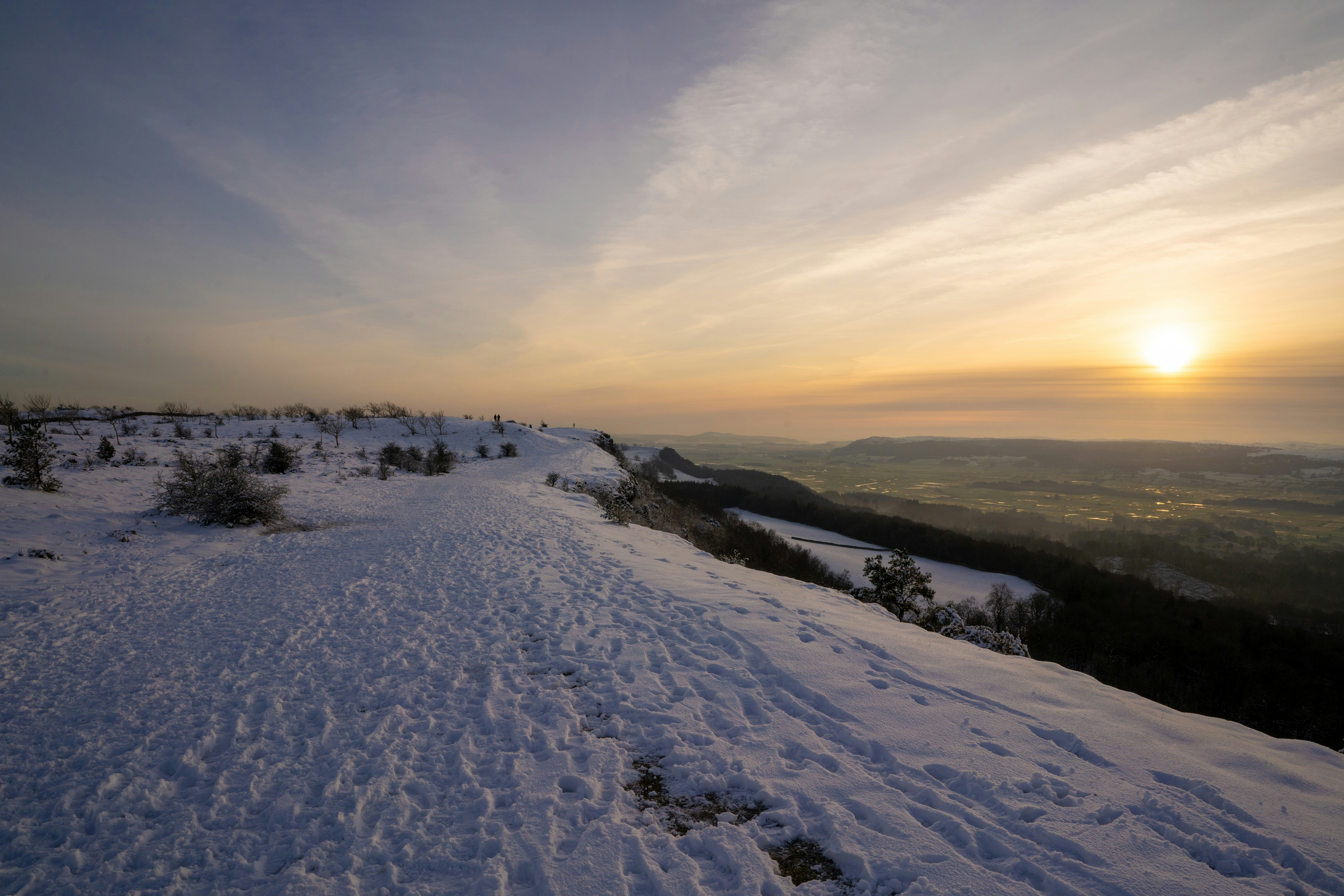 The sun is setting over a snowy hill