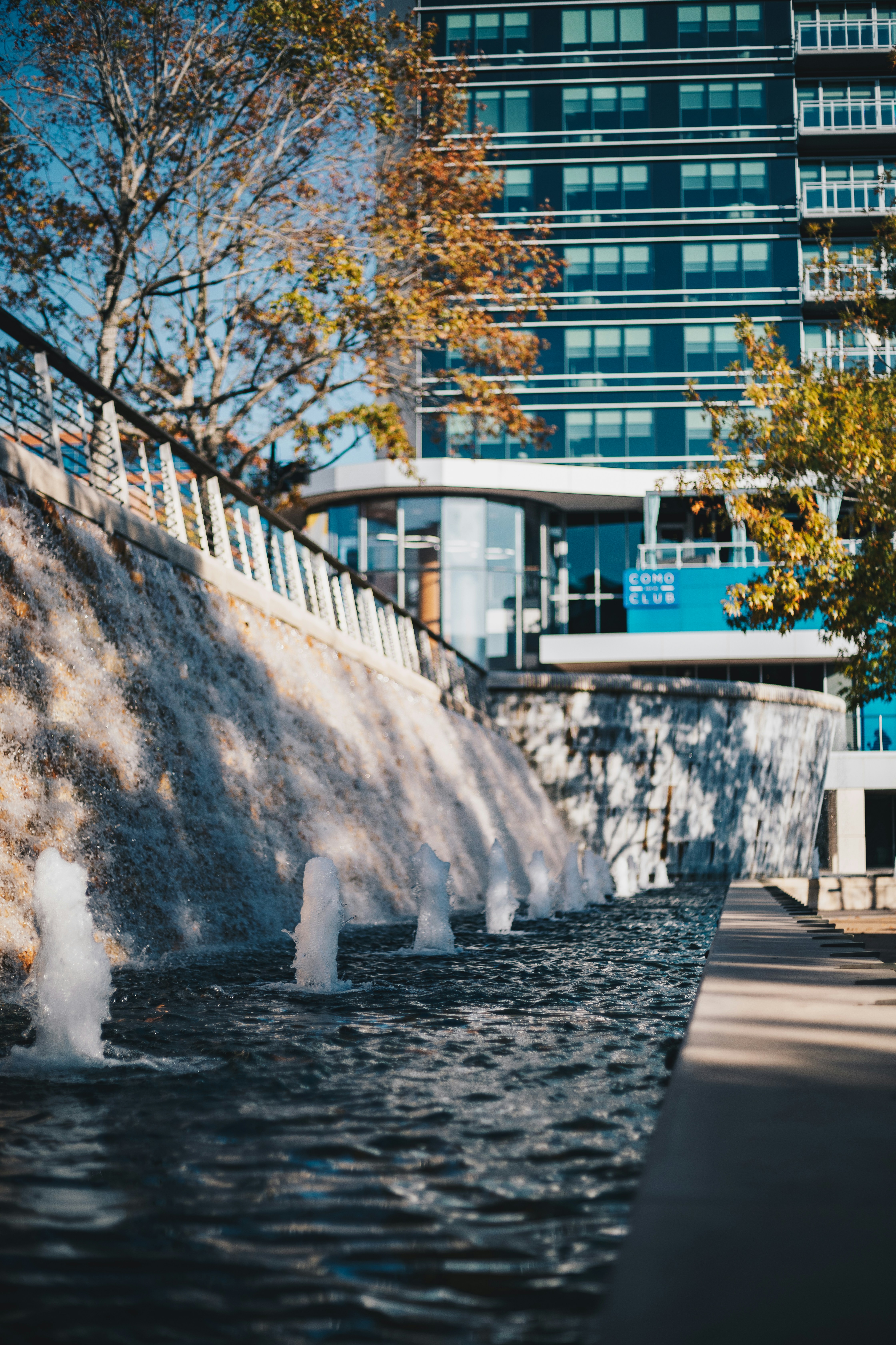 Un uomo, in sella a uno skateboard, lungo un fiume, accanto a un edificio alto