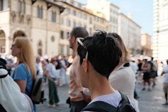A group of people walking down a street next to tall buildings