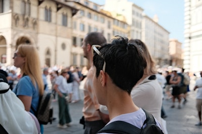 A group of people walking down a street next to tall buildings