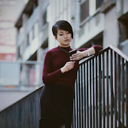 A woman leaning on a railing looking at her cell phone