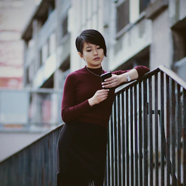 A woman leaning on a railing looking at her cell phone