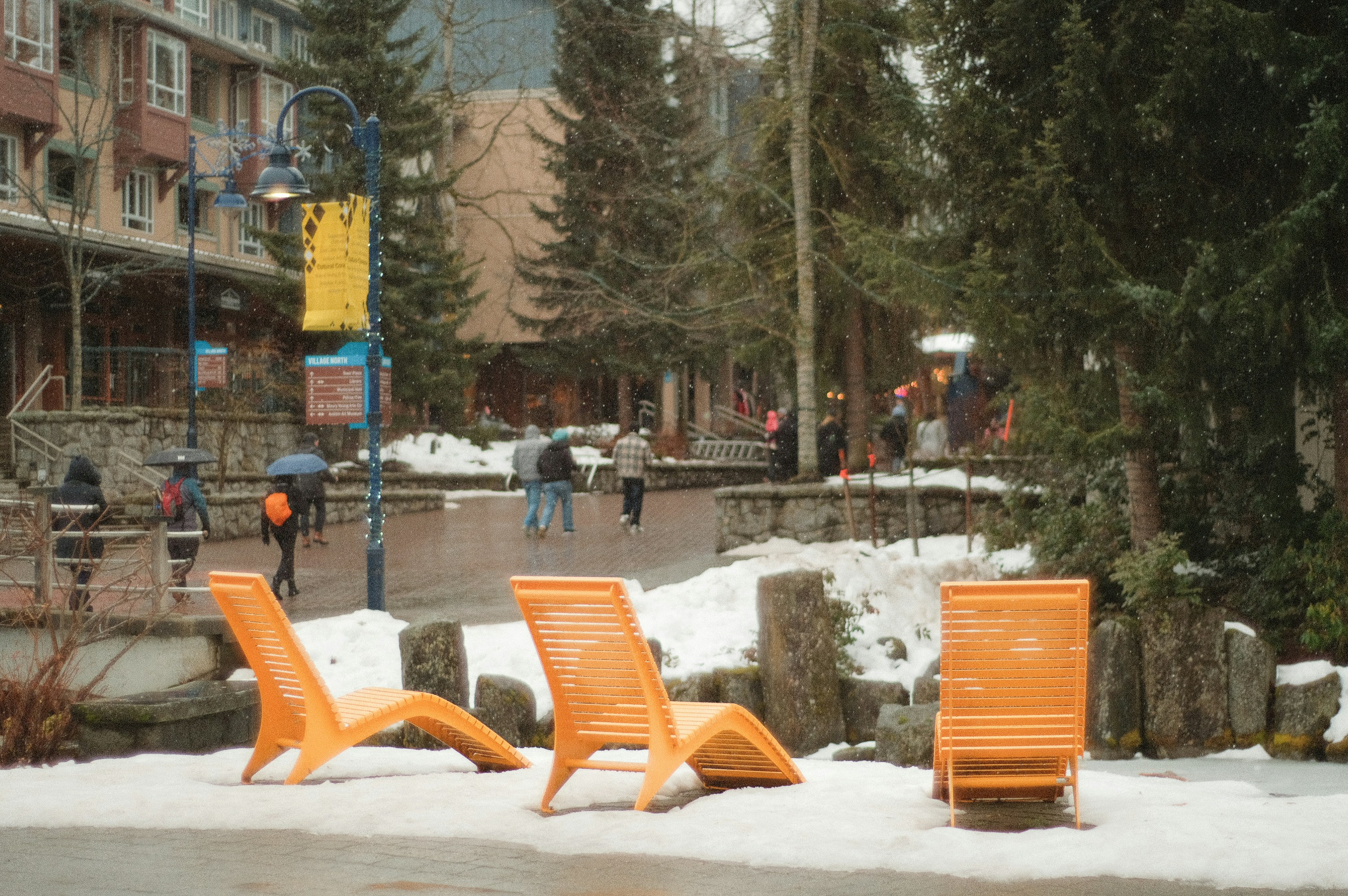 A couple of orange chairs sitting on top of snow covered ground