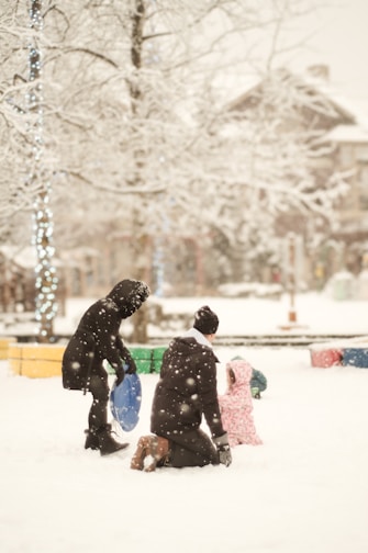A couple of people that are in the snow prepairing it for plow trucks