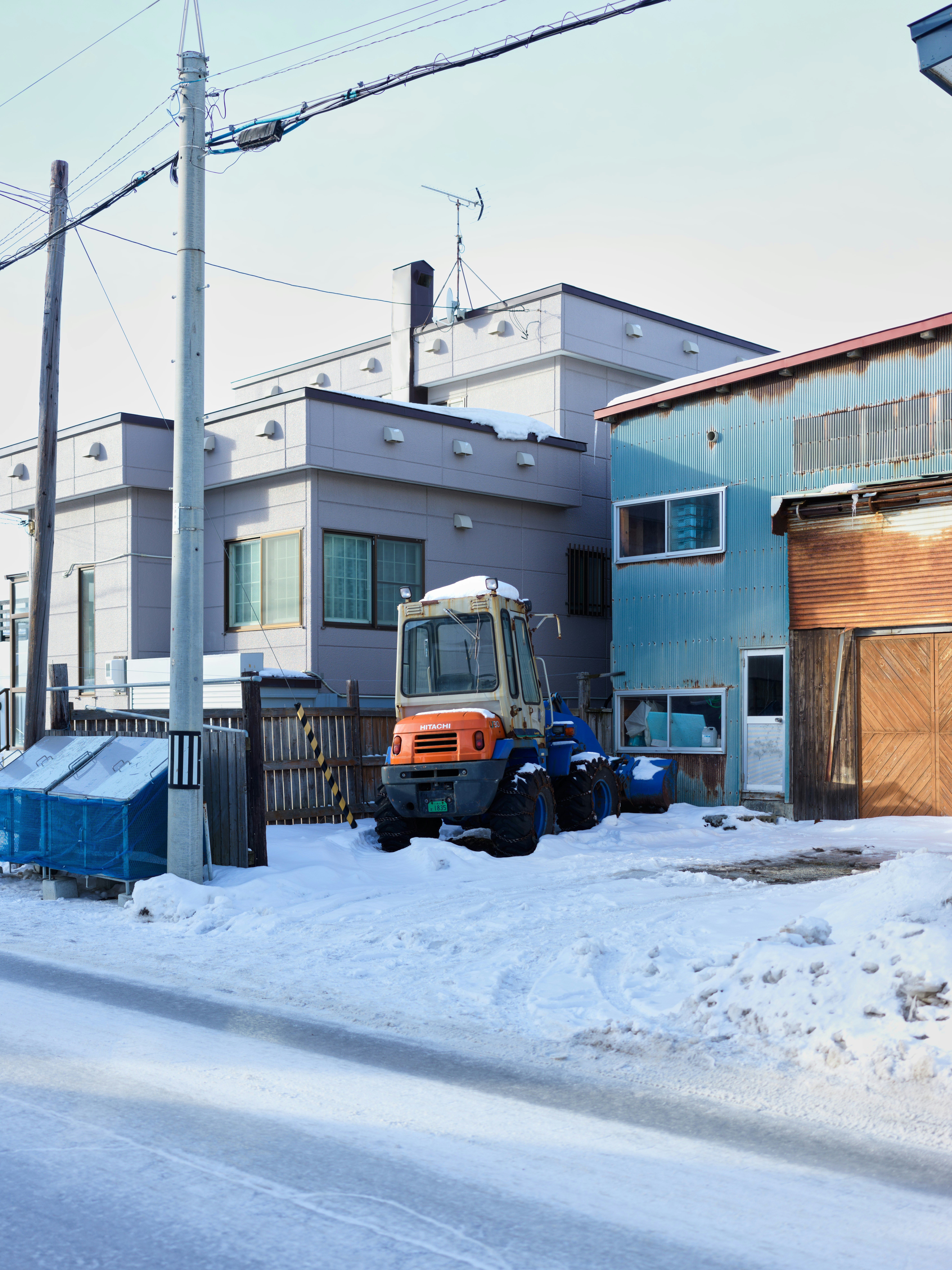 A snow plow is parked in front of a row of houses