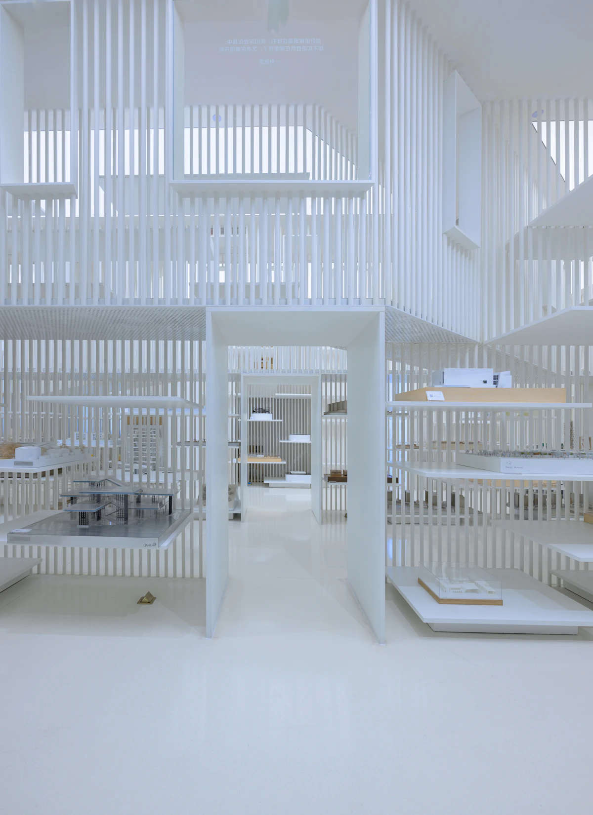 White model room lined with slatted partitions and shelves holding architectural study models.