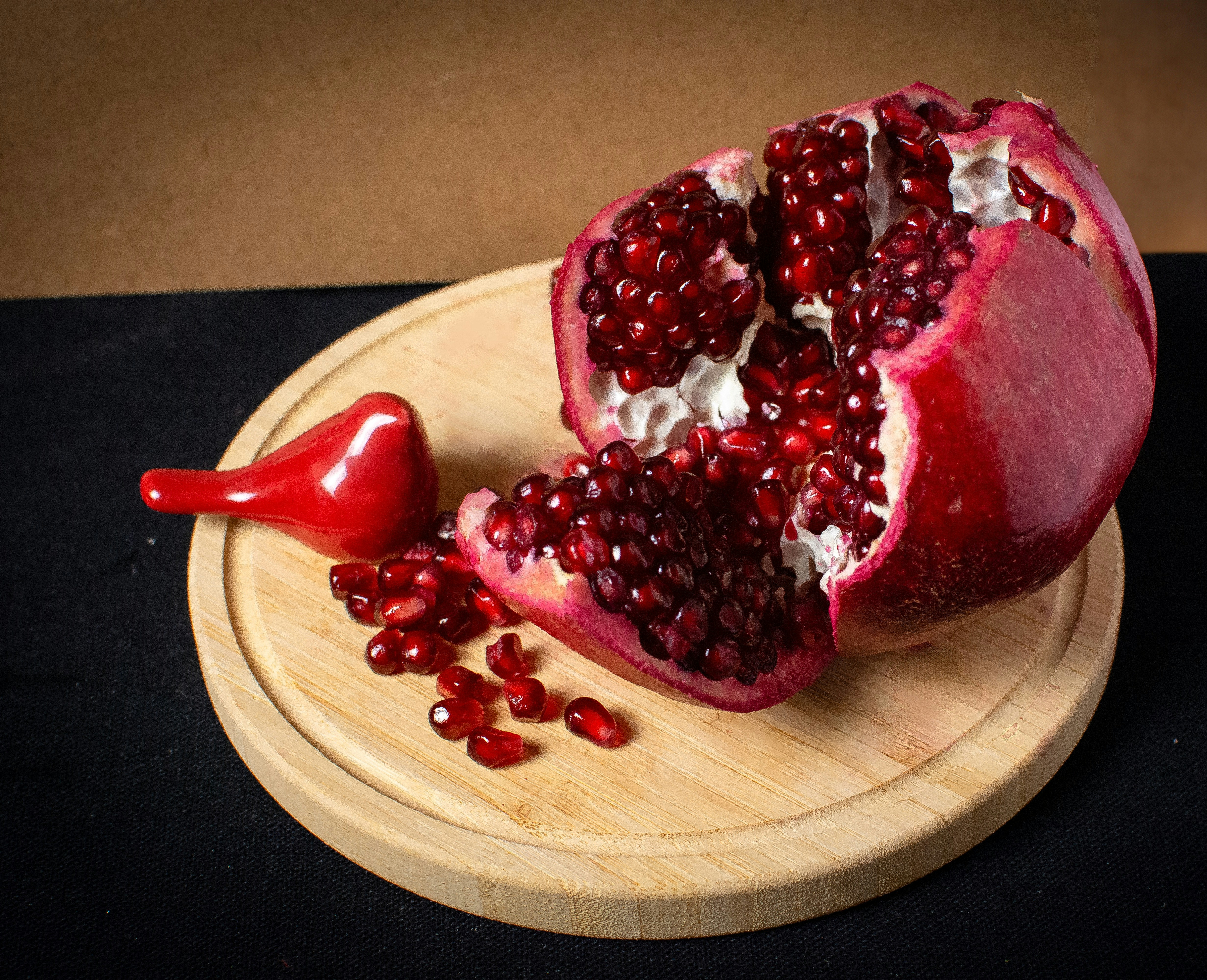 Pomegranate seeds scattered like garnets across a dark wooden board