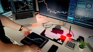 A man sitting at a desk with two monitors and a laptop