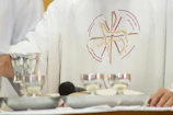 A priest standing in front of a table with silver cups