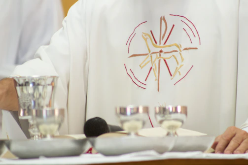 A priest standing in front of a table with silver cups
