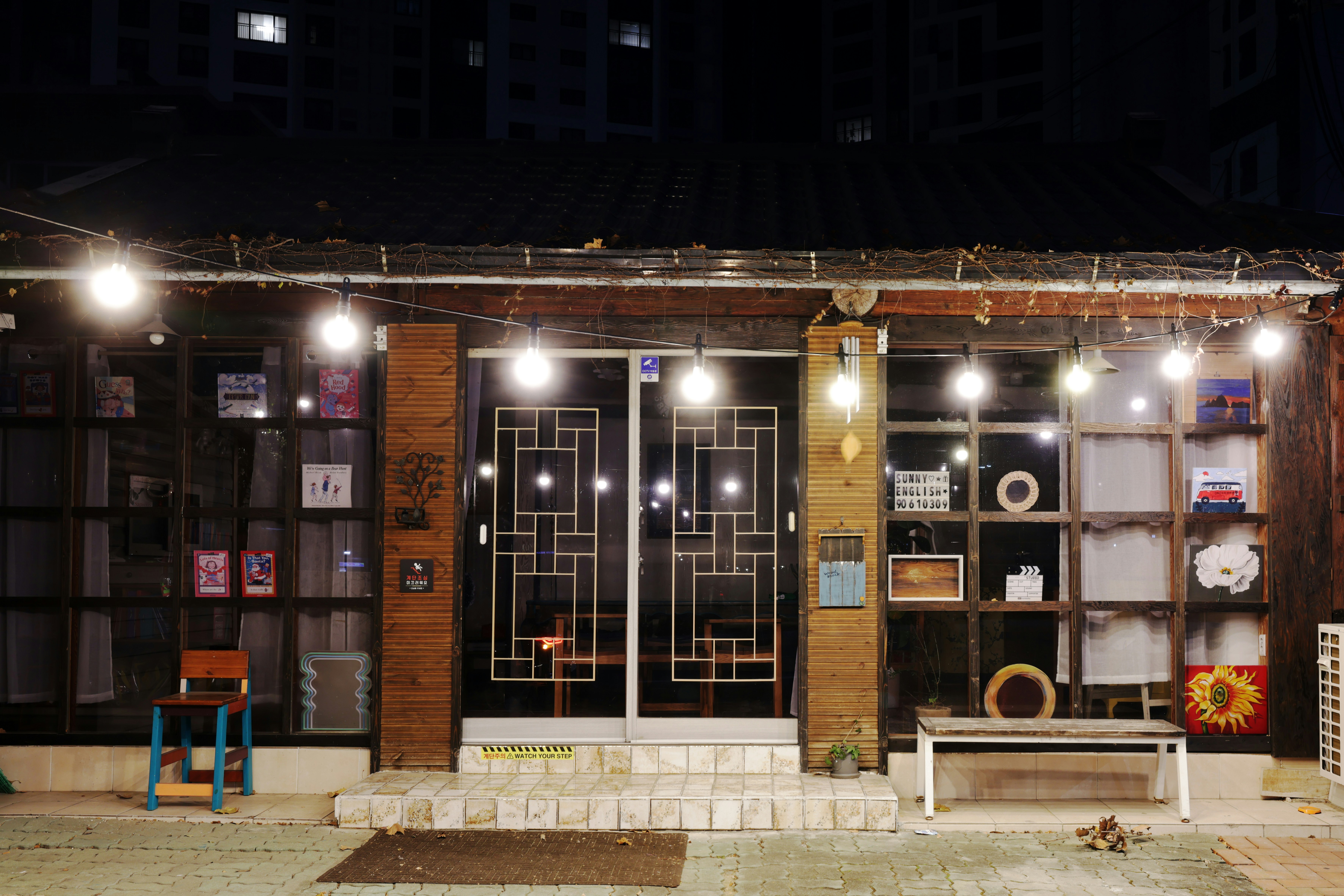Cafe storefront window with vinyl name lettering and hours, warm daylight