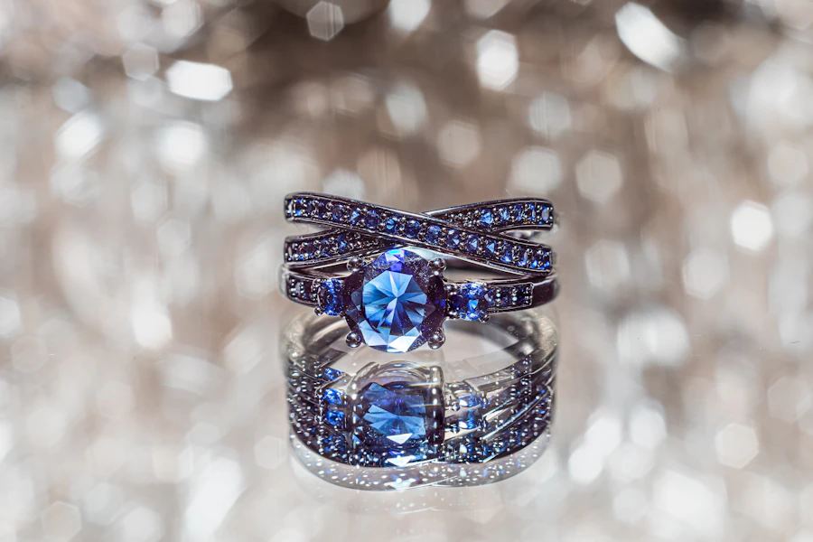 A sapphire ring with crossed, pavé-set bands, photographed against soft points of light