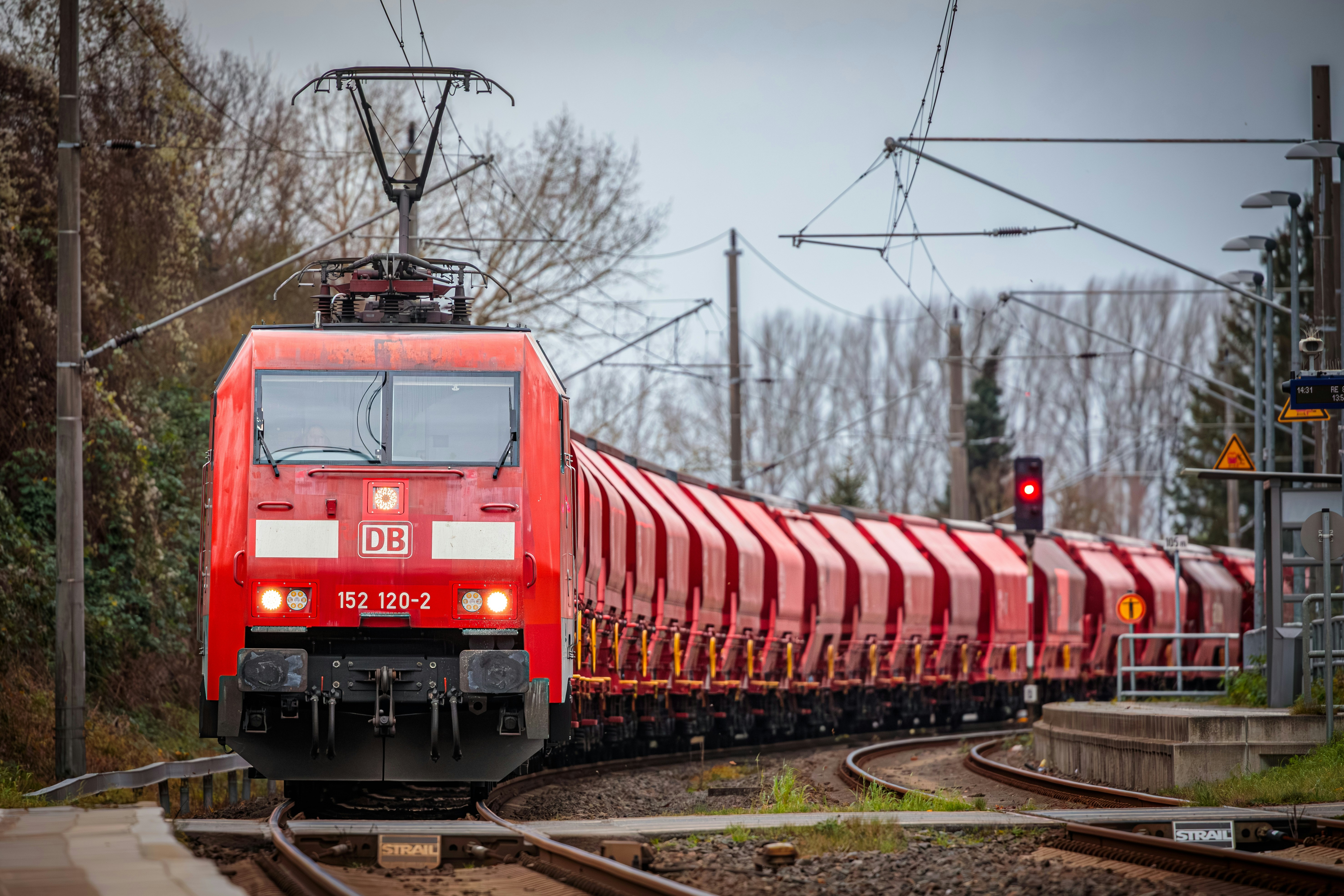 A red train traveling down train tracks next to a forest