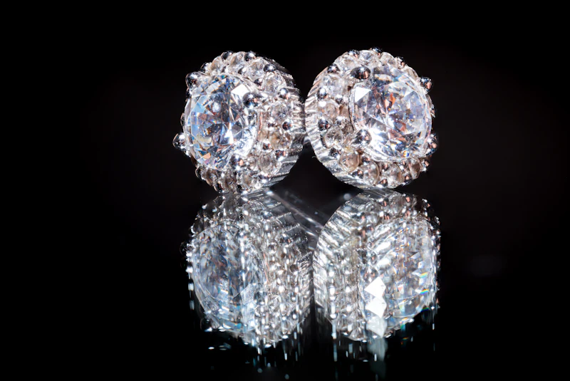 Pair of round halo diamond stud earrings reflected on black glass