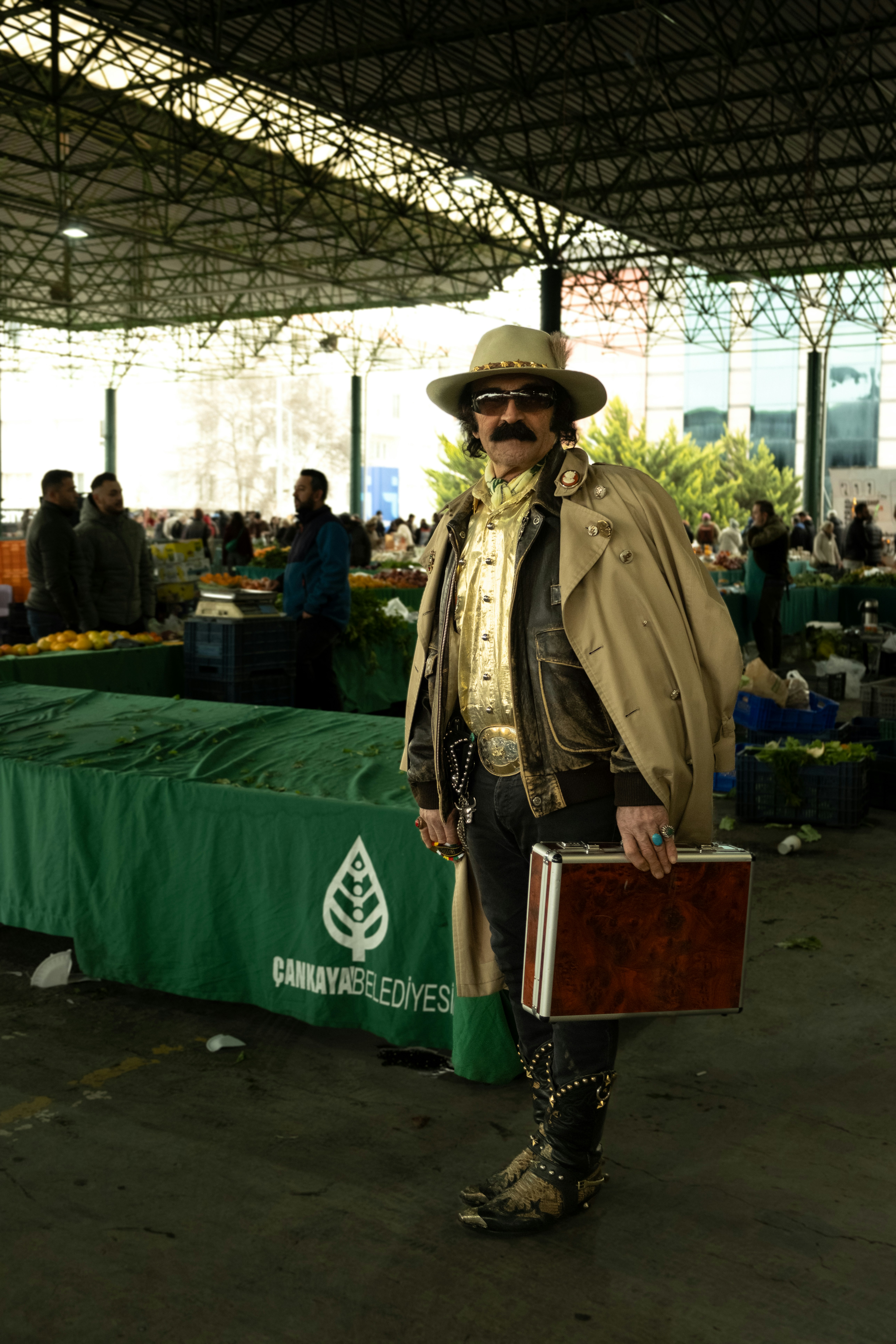 A man in a hat and trench coat holding a briefcase