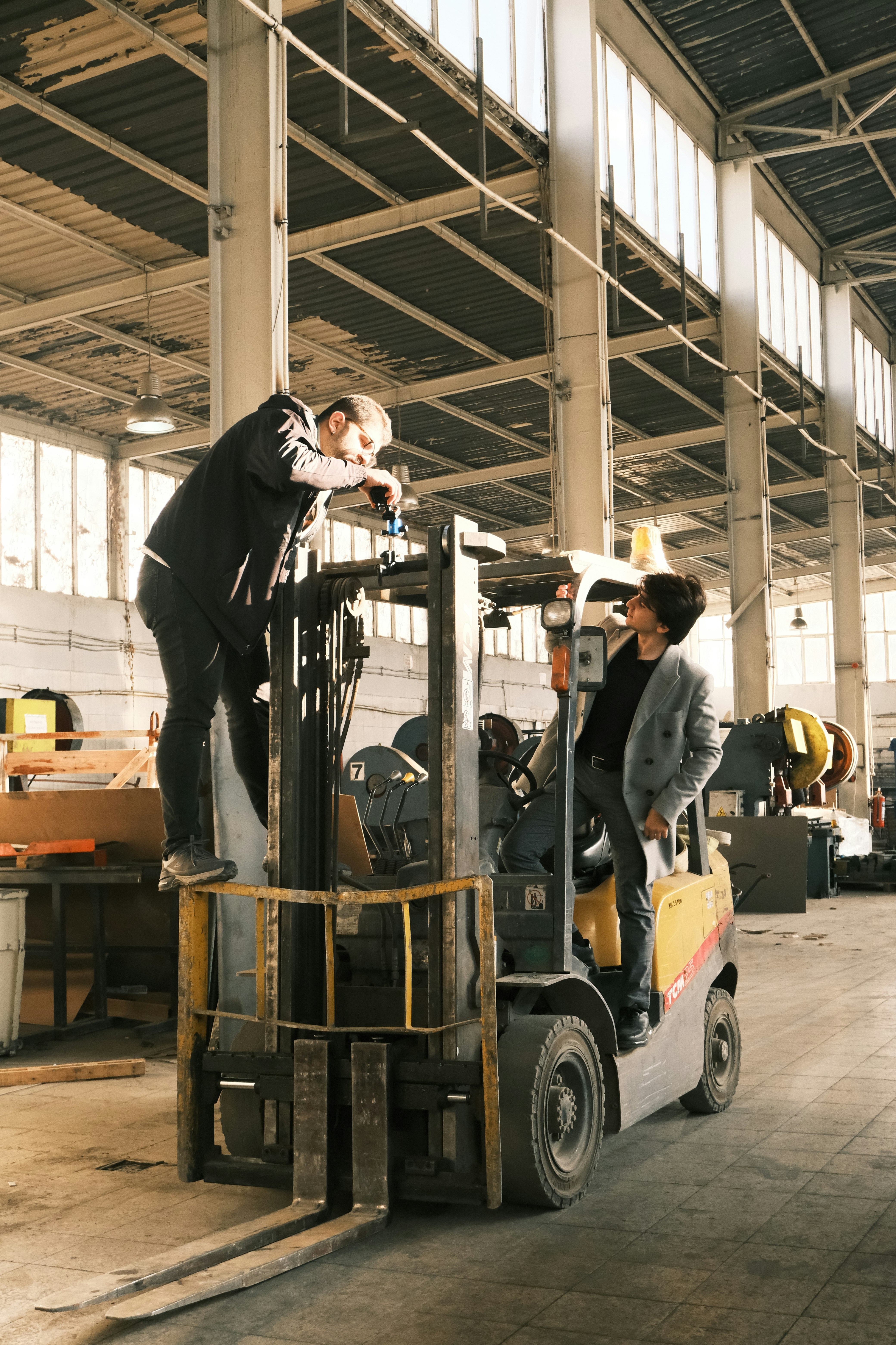 A man standing on top of a forklift in a warehouse