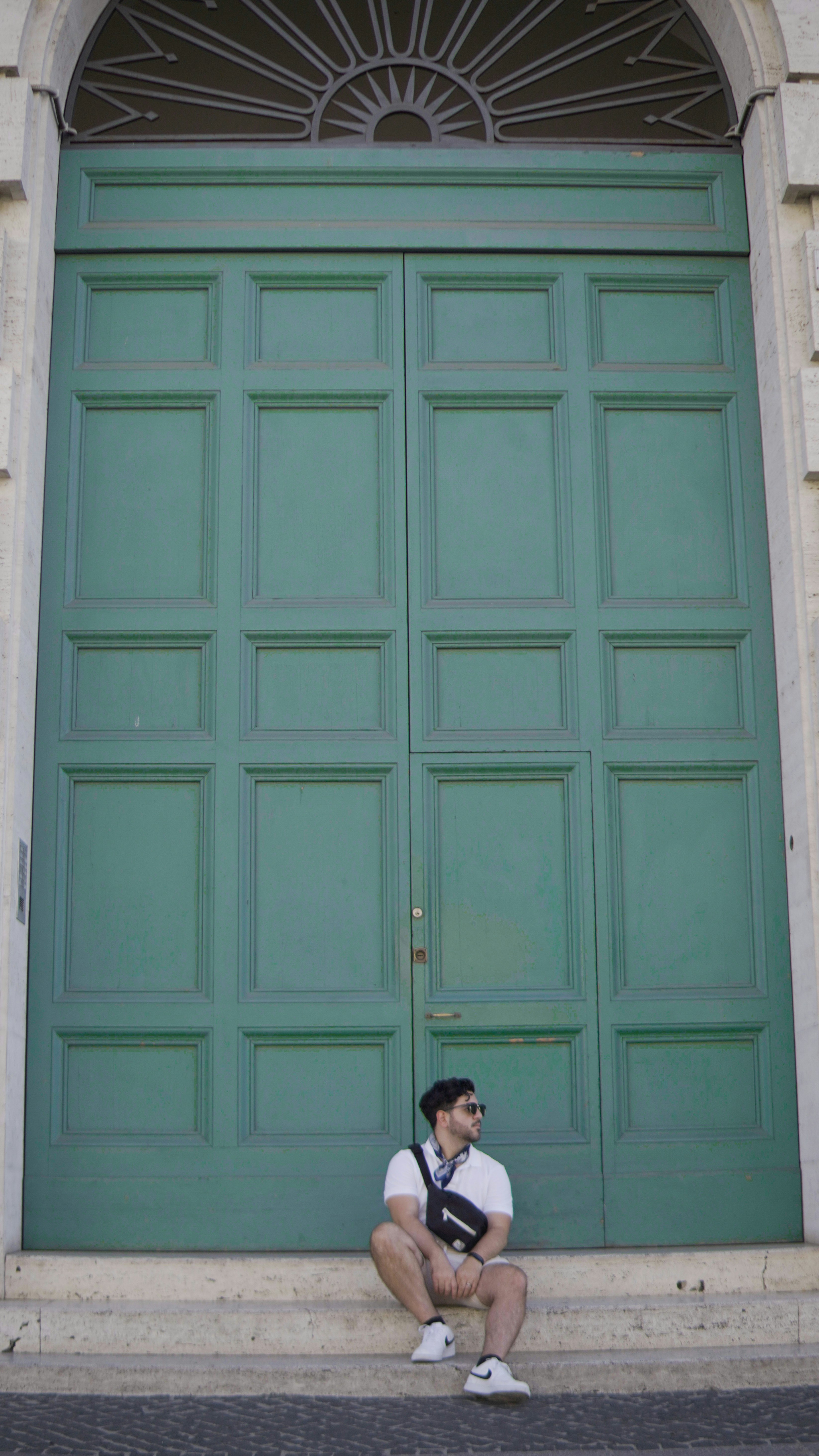 A man sitting in front of a green door