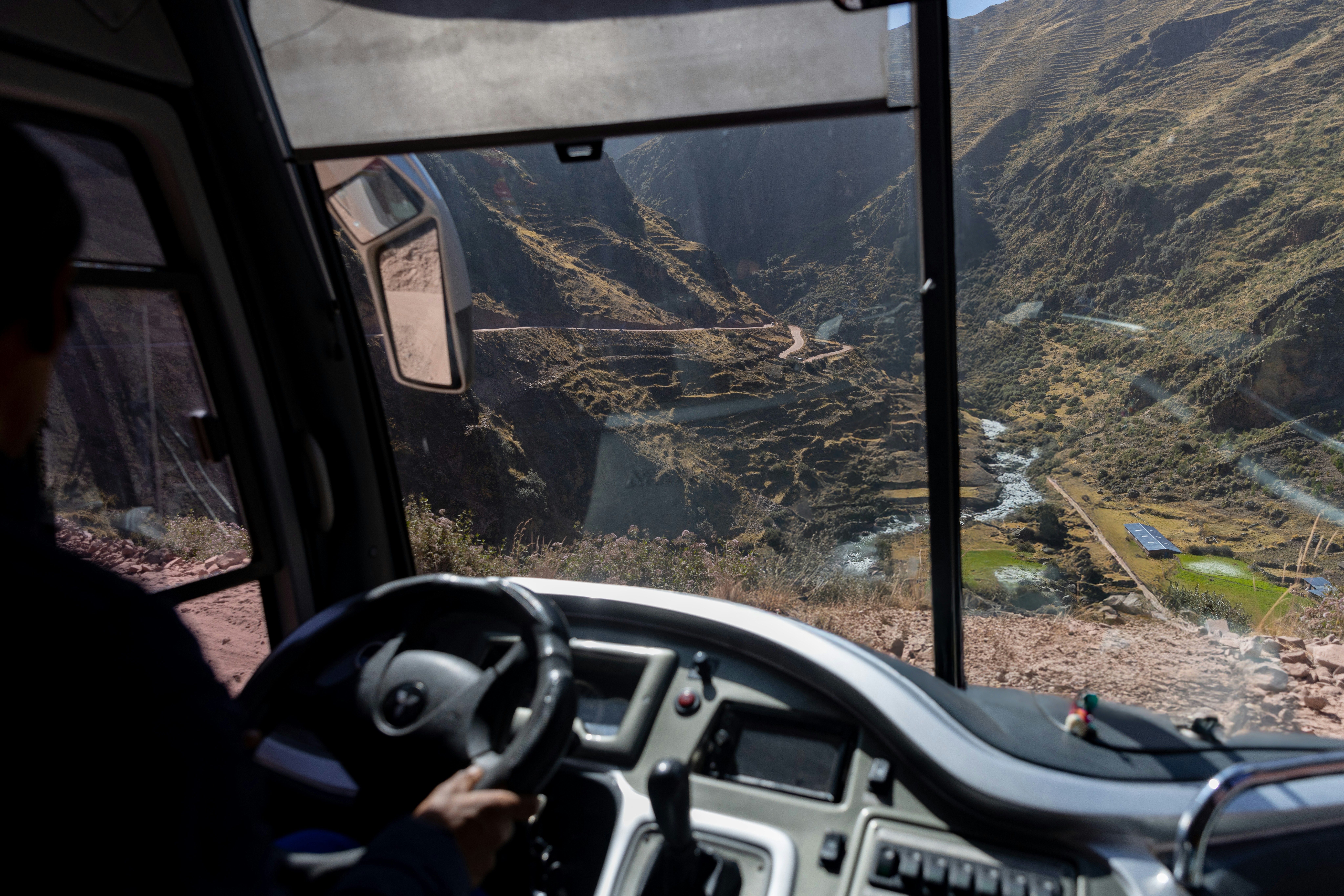 A man driving a bus down a mountain road