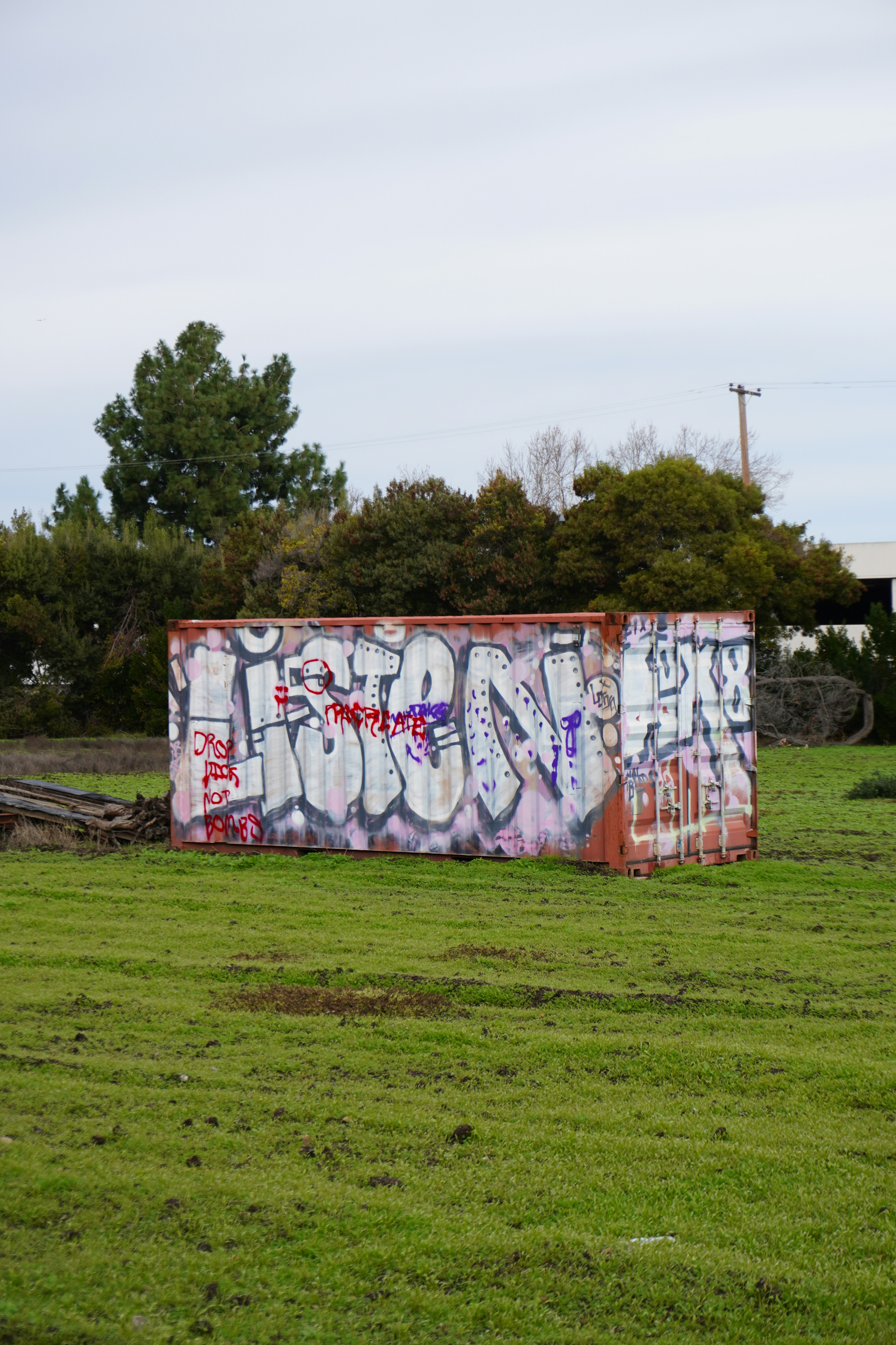 A graffiti covered box sitting in a field