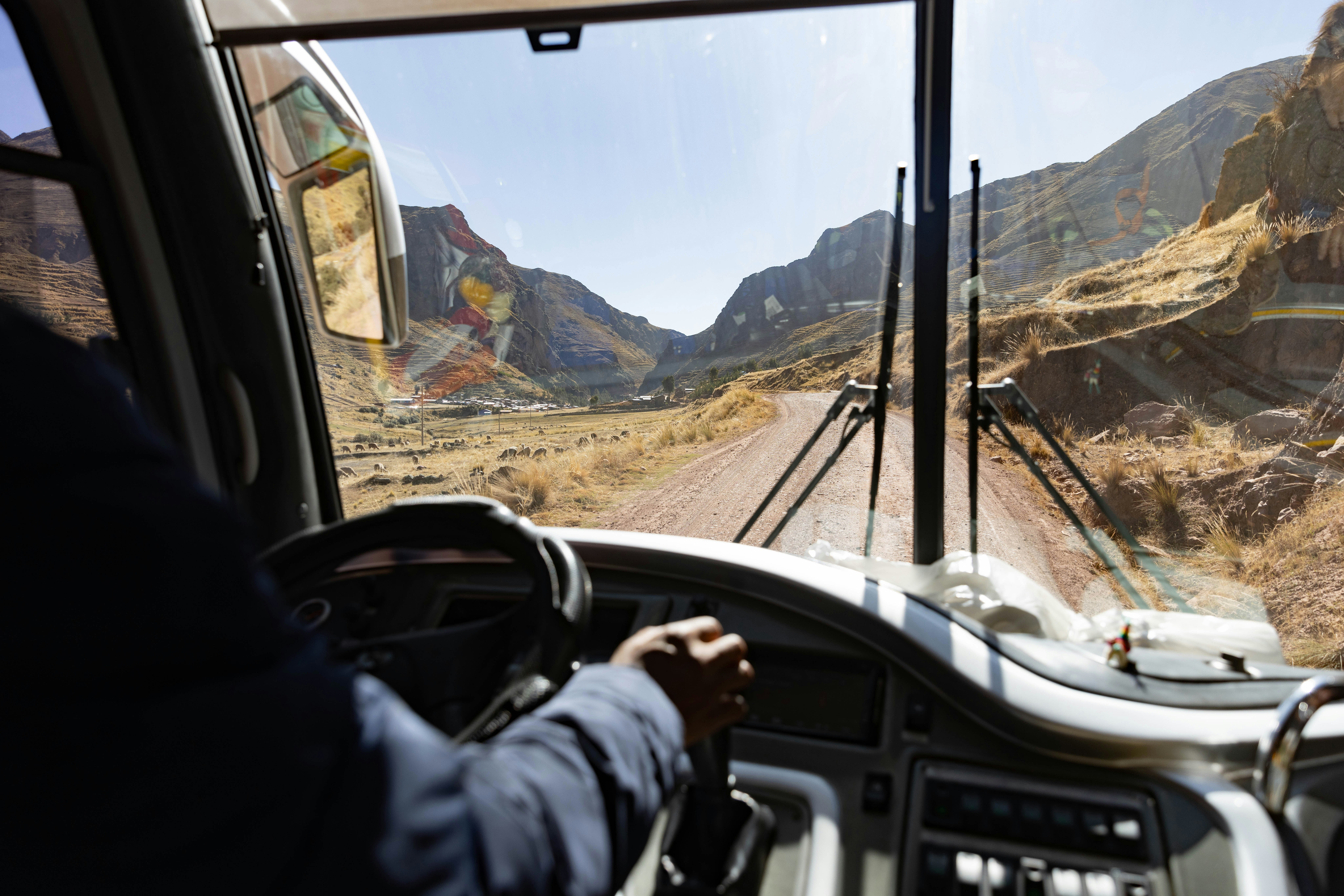 A man driving a bus down a dirt road