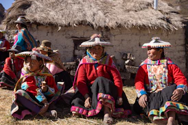 A group of people sitting next to each other in front of a hut