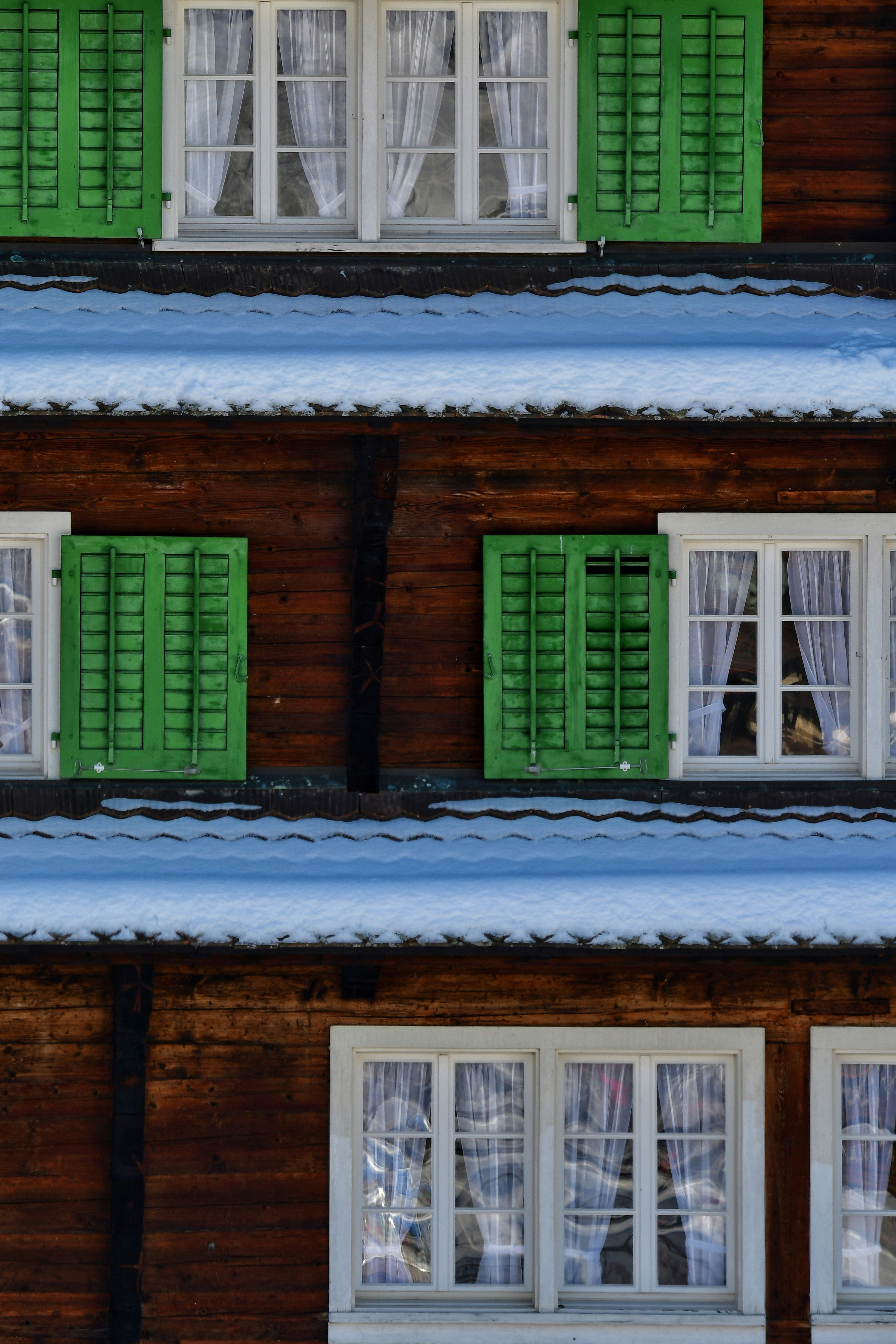 A building with green shutters and snow on the ground