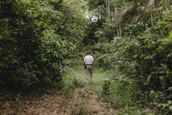 A man walking down a dirt path in the woods