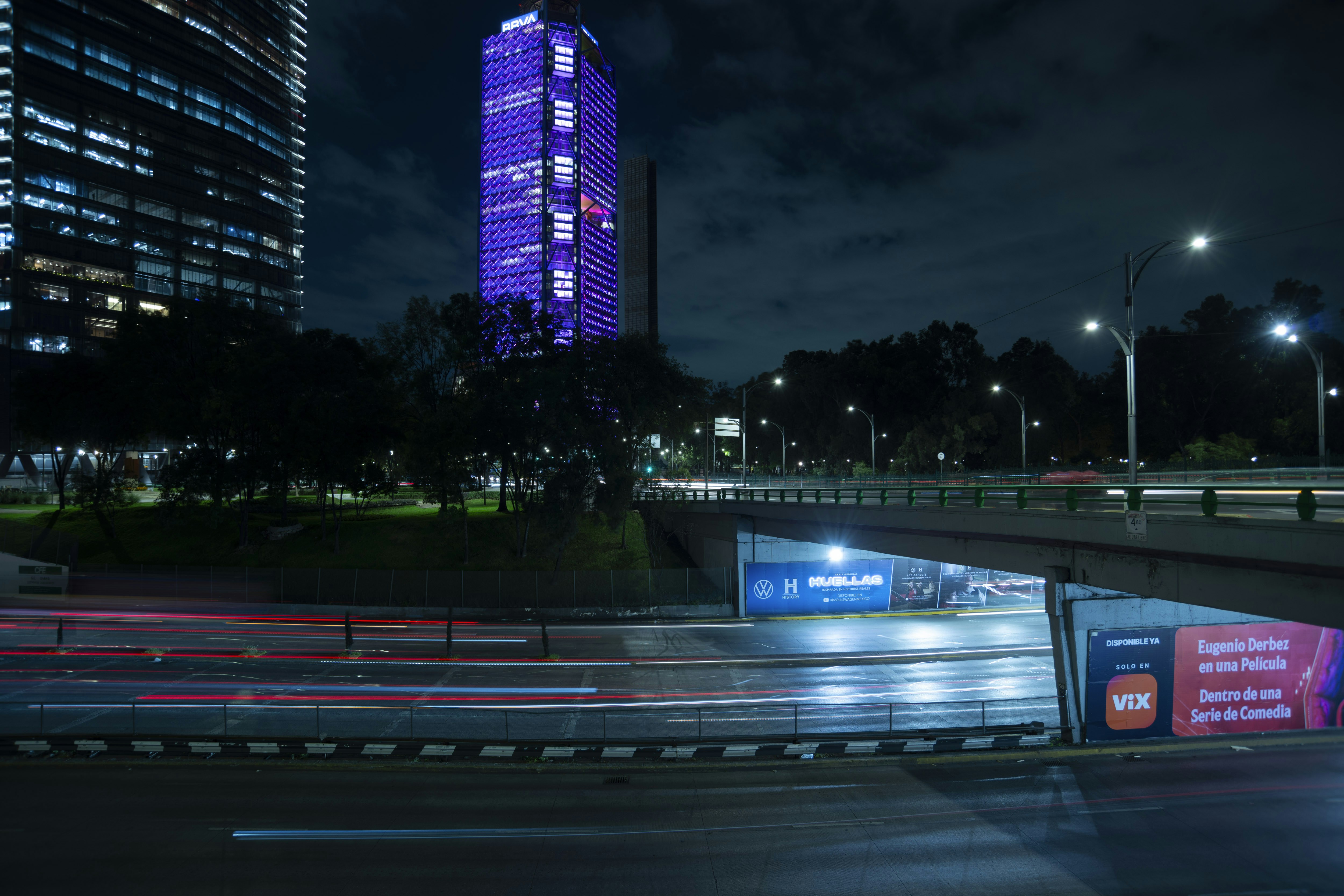 A city street at night with a tall building in the background