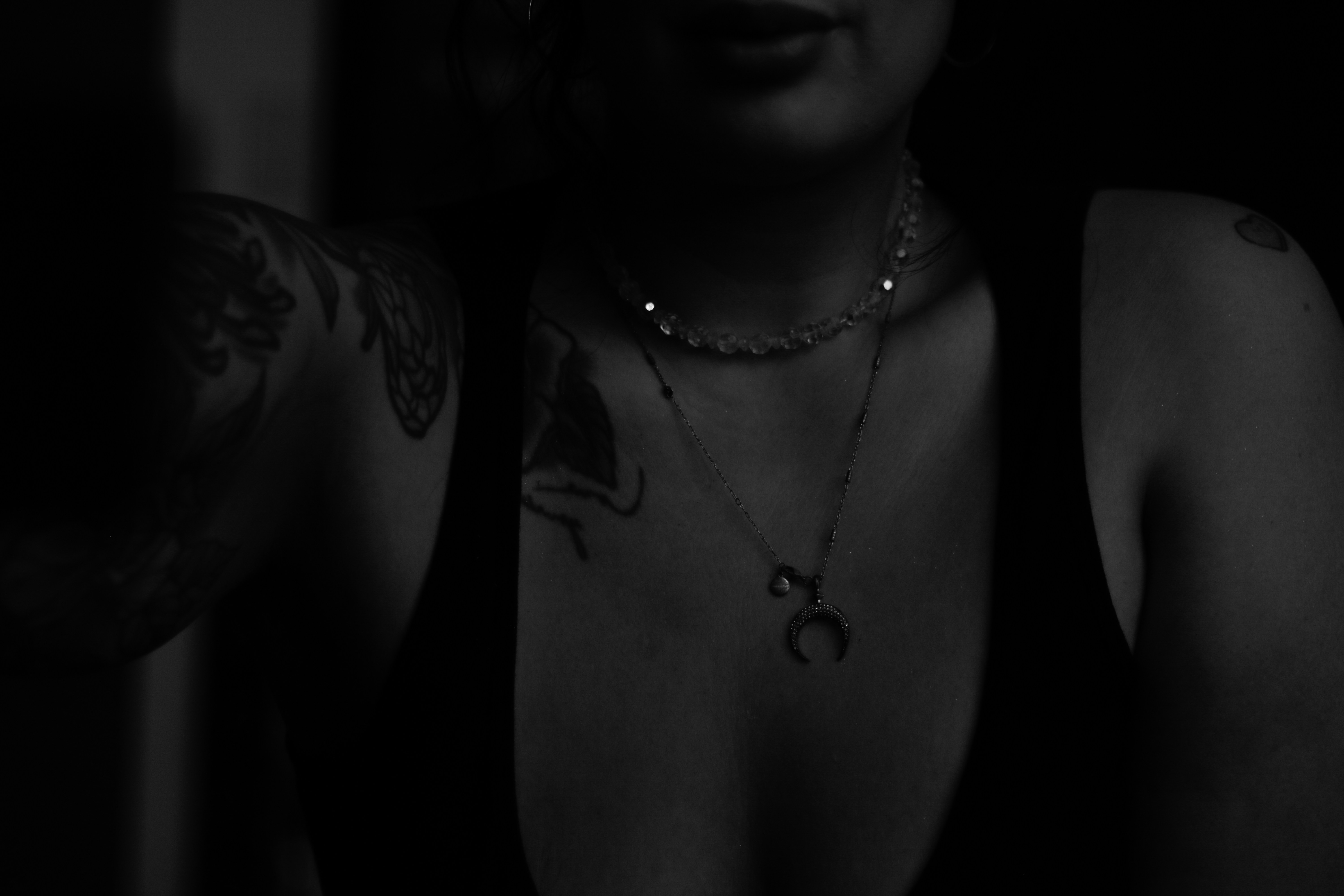 A woman in a dark room with tattoos on her chest