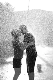 Two people standing under an umbrella in the rain