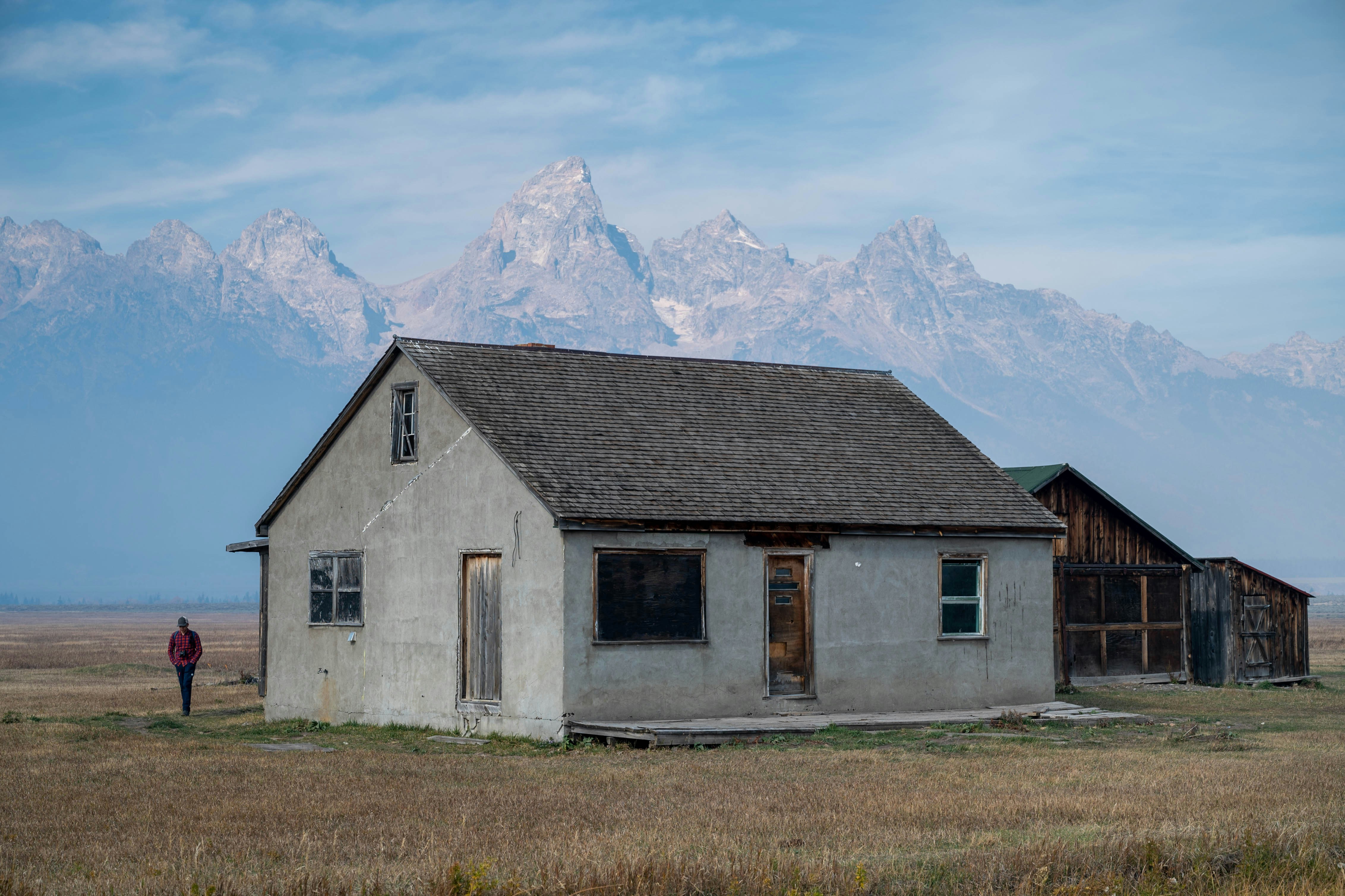 An old house in a field with mountains in the background