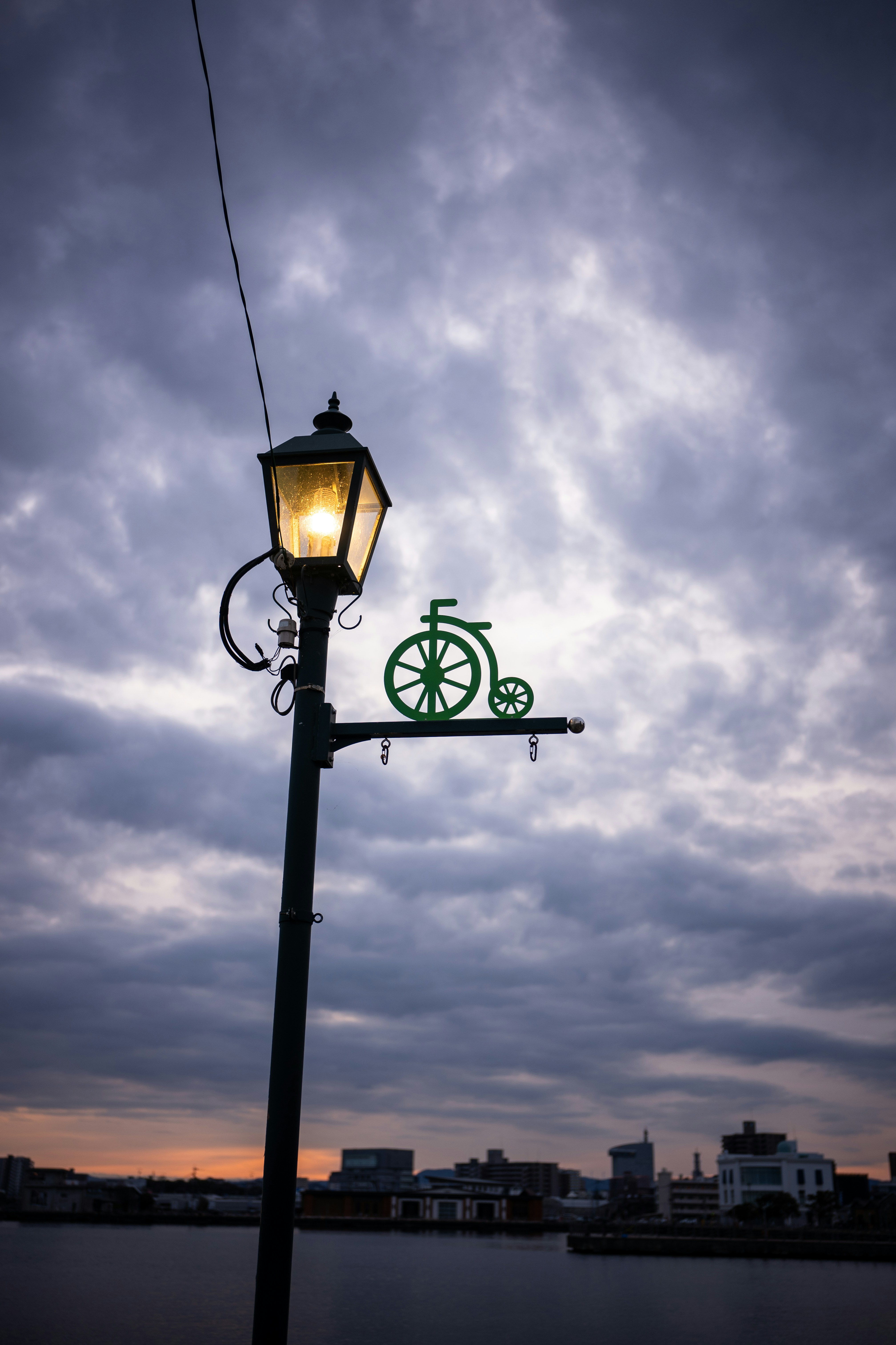 A lamp post with a bicycle on it in front of a cloudy sky