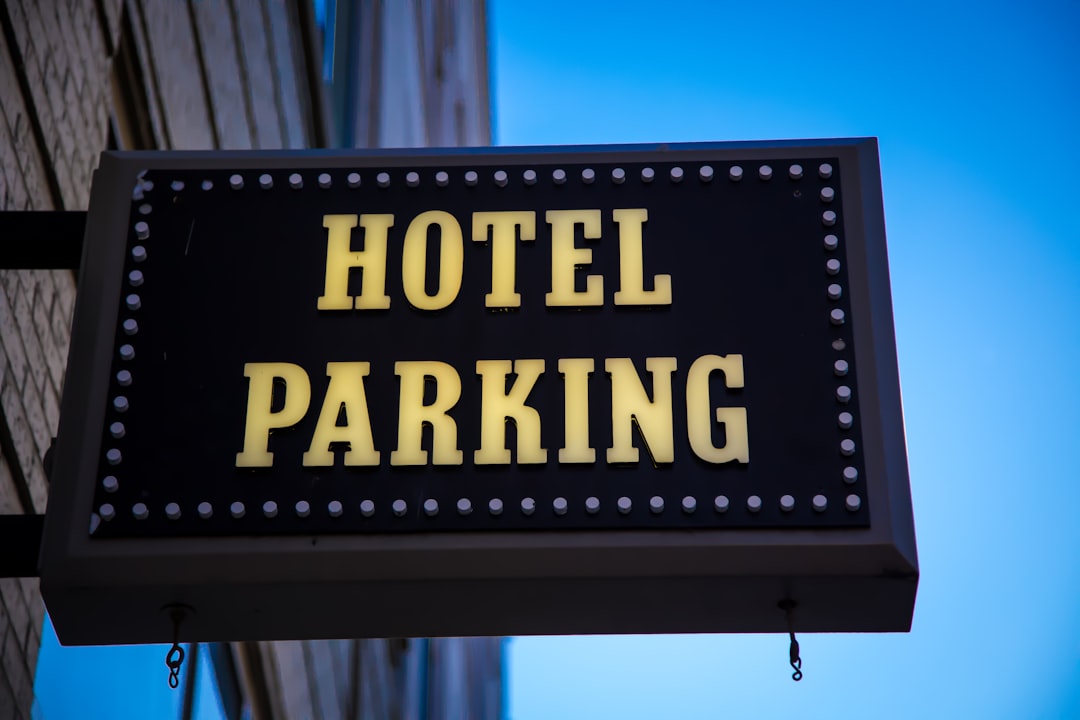 A hotel parking sign hanging from the side of a building,