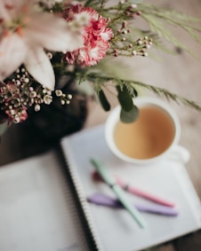 A cup of coffee sitting on top of a table next to a notebook