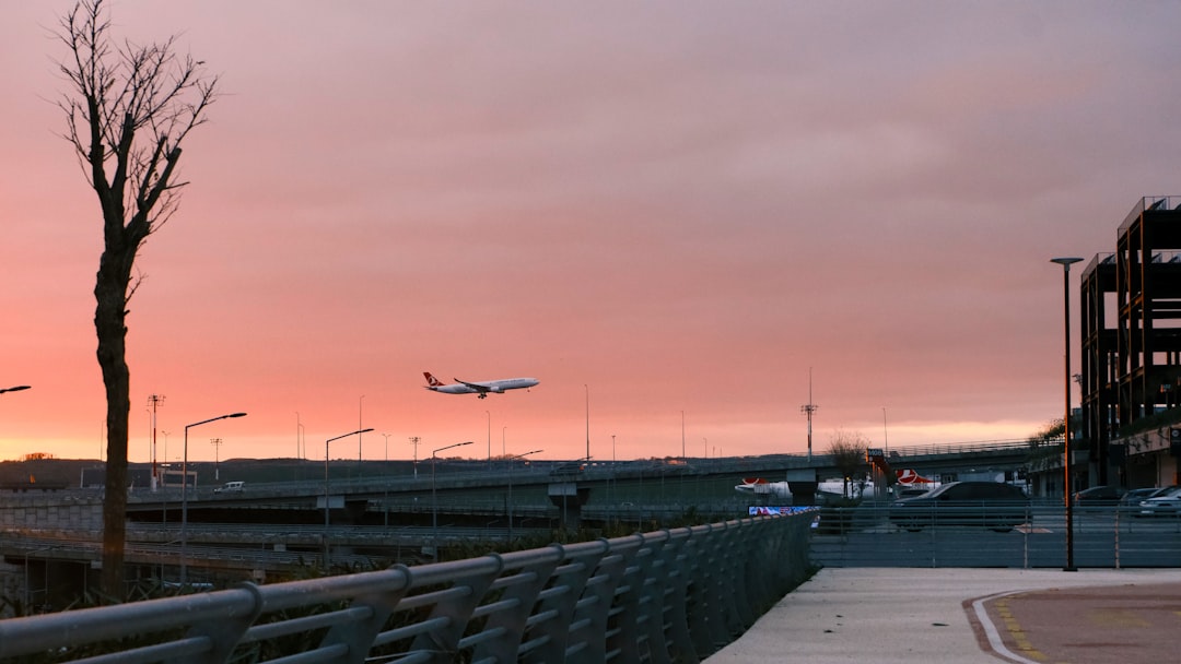 An airplane is flying over a parking lot,