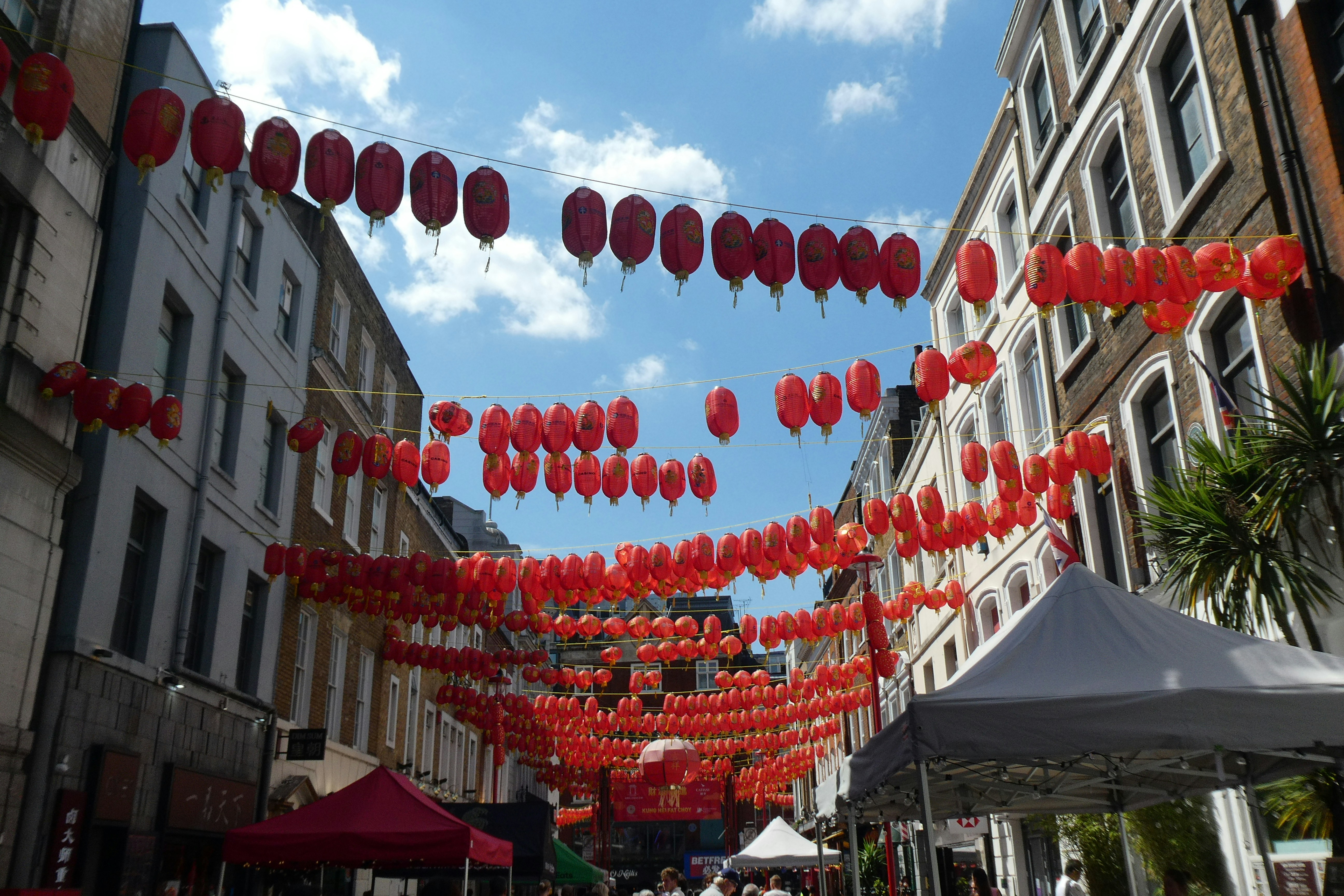 A group of people walking down a street next to tall buildings